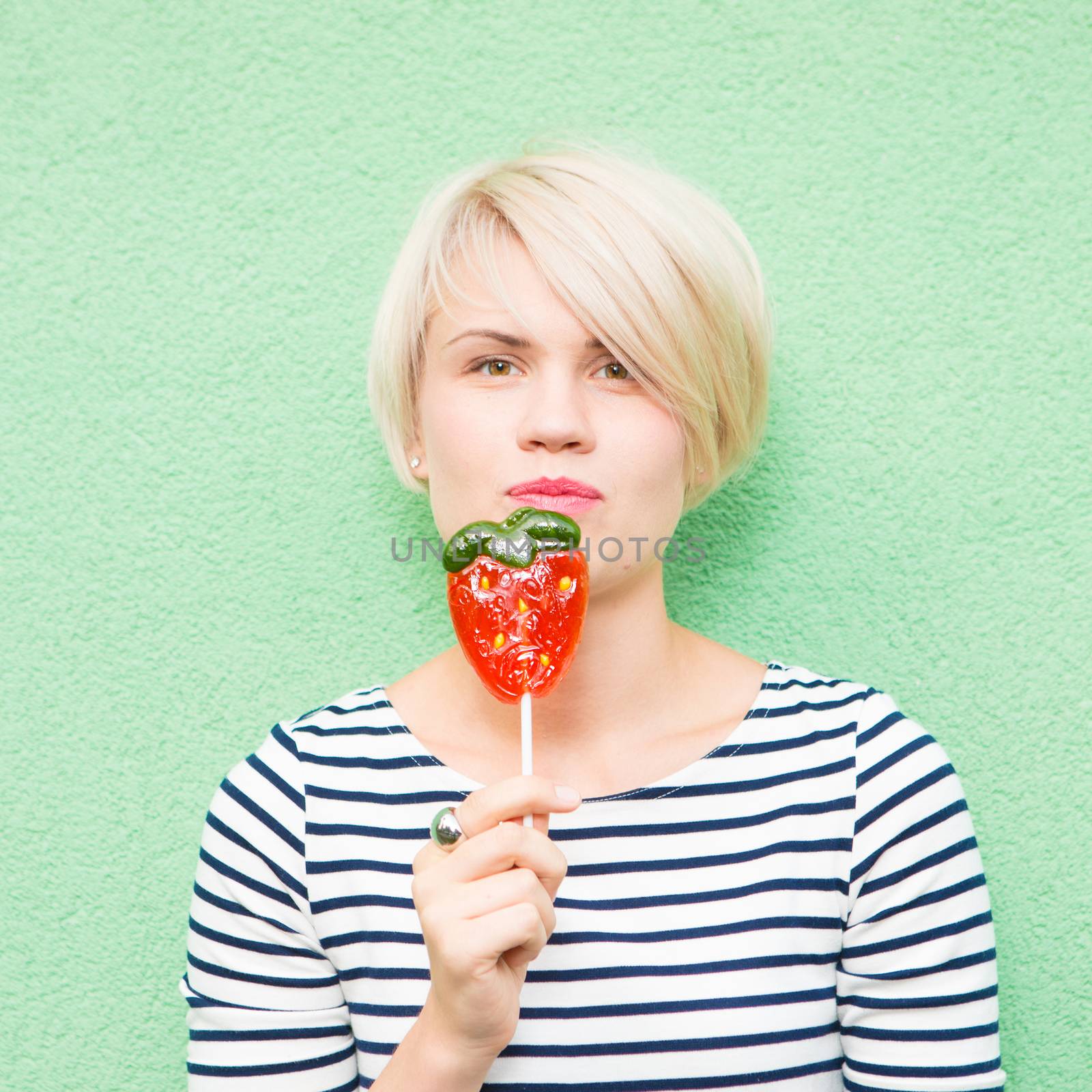 Young sexy woman sucking lollipop. Urban style. Outdoors, lifestyle.