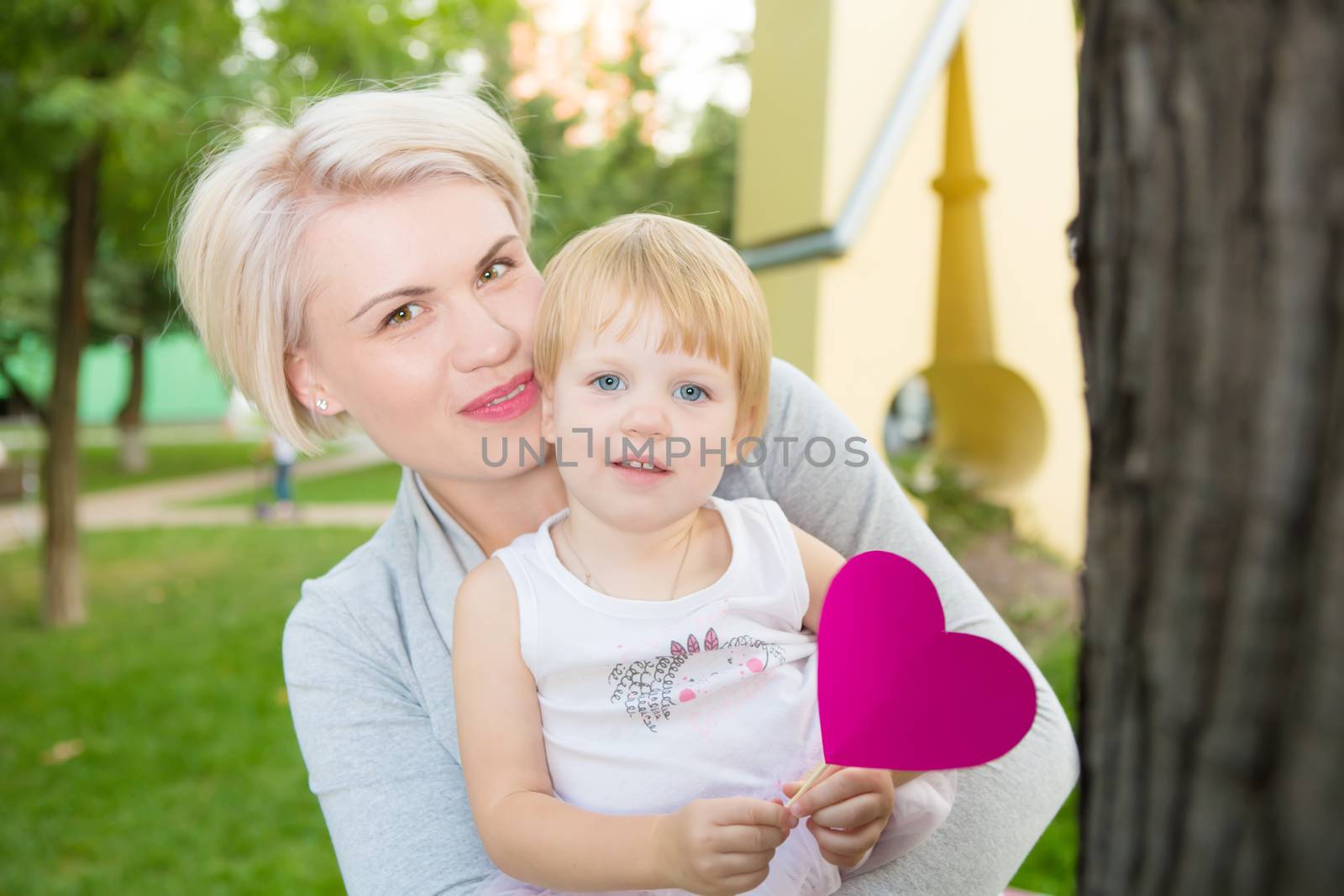 portrait of beautiful mother and kid girl outdoors in park by sarymsakov