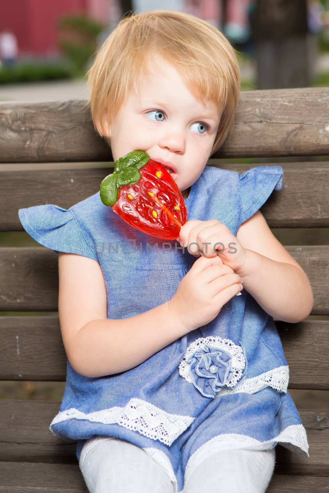 Beautiful little girl holding strawberry shaped lollipop by sarymsakov