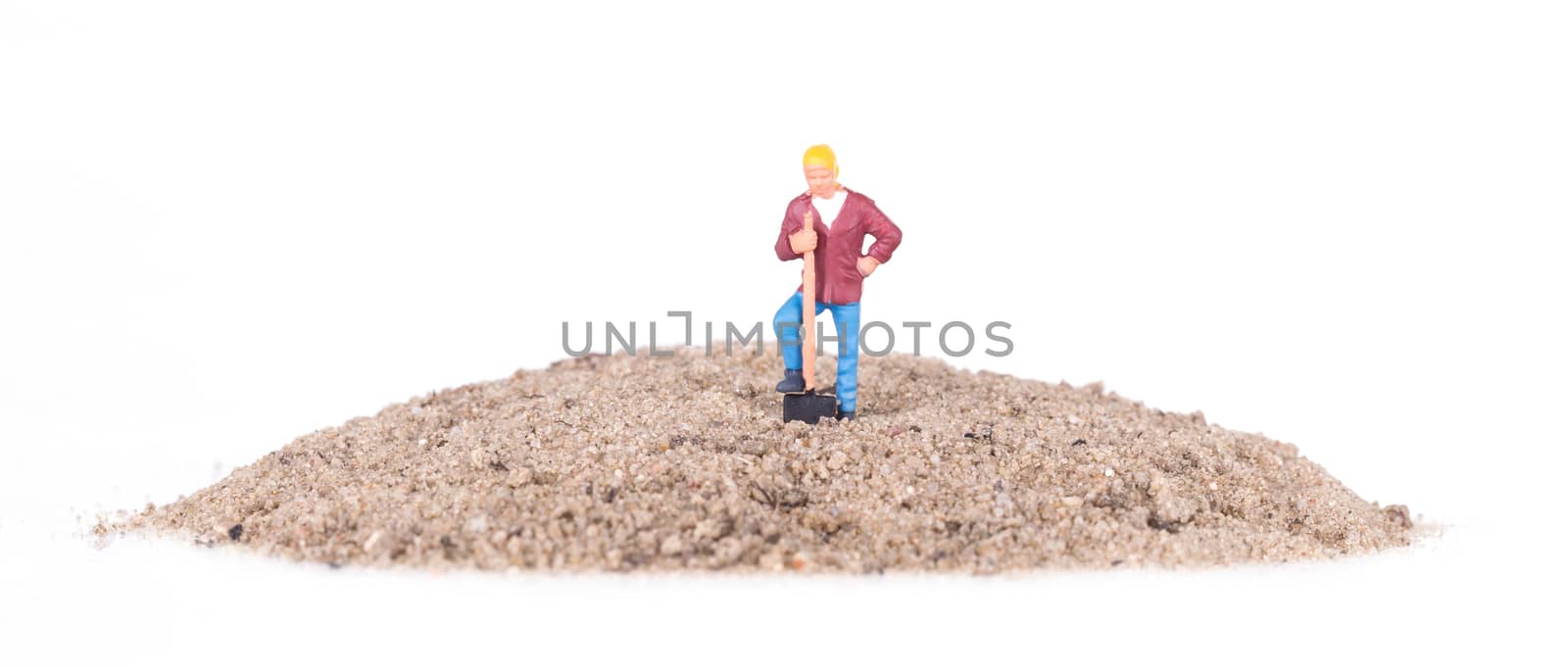 Miniature worker with a shovel on a mountain of sand