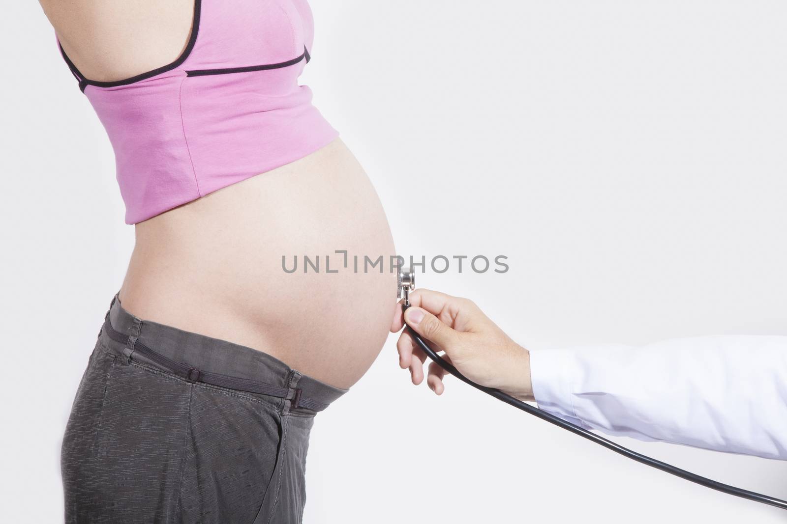 doctor hand with stethoscope on tummy of naked pregnant woman