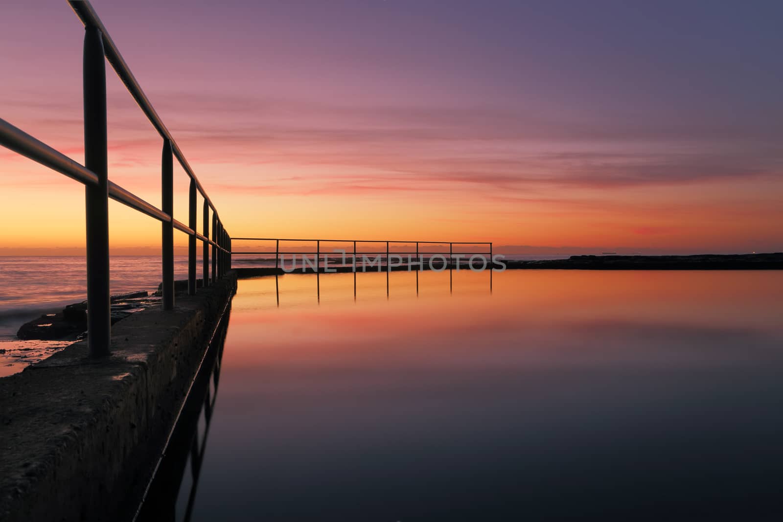 Looking across the ocean rock pool at Wombarra NSW Australia with a beautiful sunrise sky reflected in the pools water.