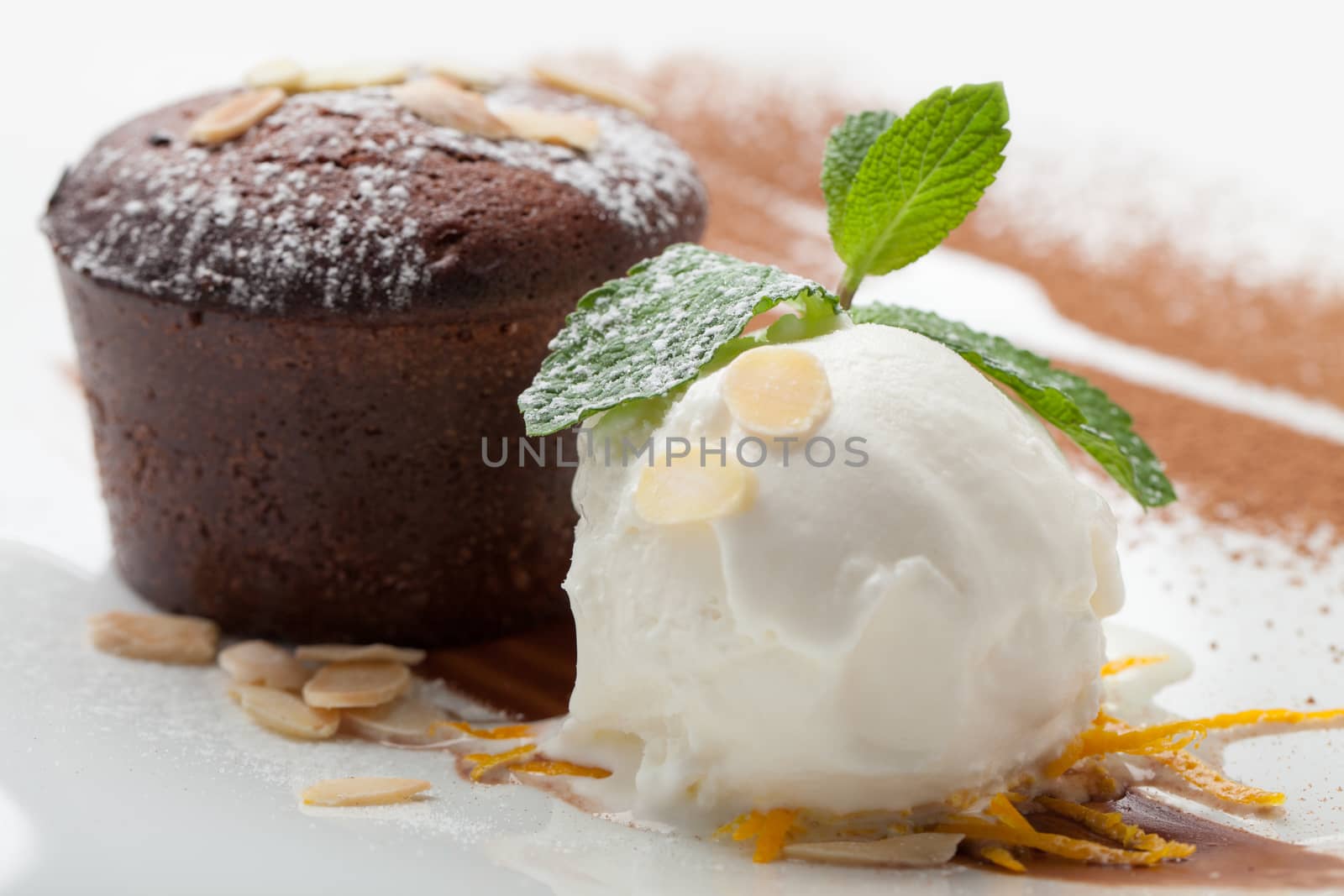 Warm dessert chocolate cake Fondant served on plate with ice-cream ball, almond chips, mint, icing, citron, cacao