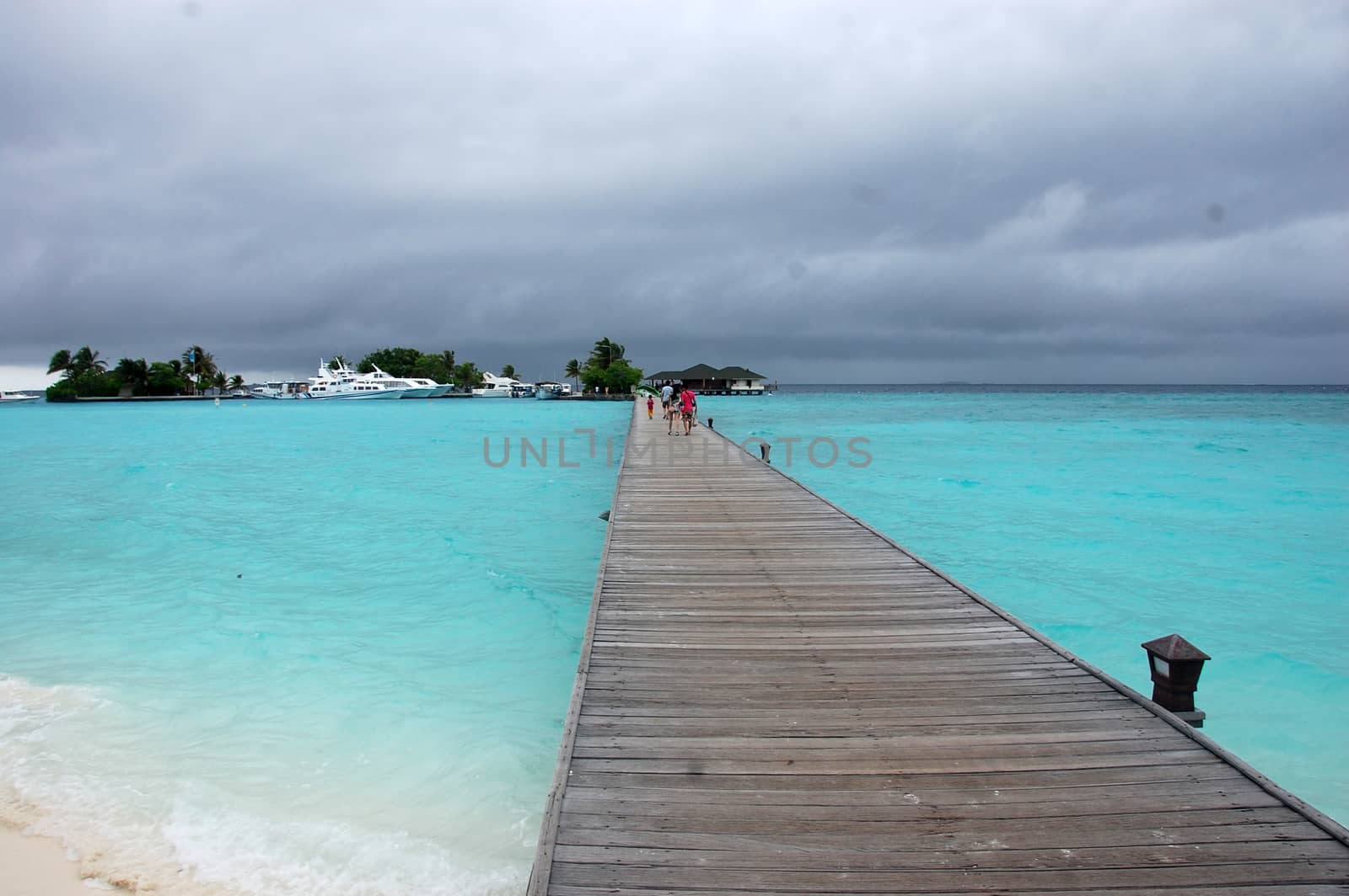 People at long timber pier Paradise Island Resort Maldives
