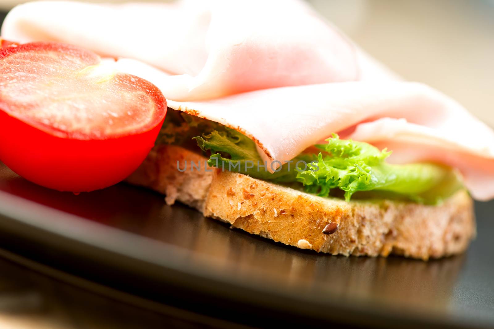 Open-faced  sandwich with ham, tomato and salad leaves
