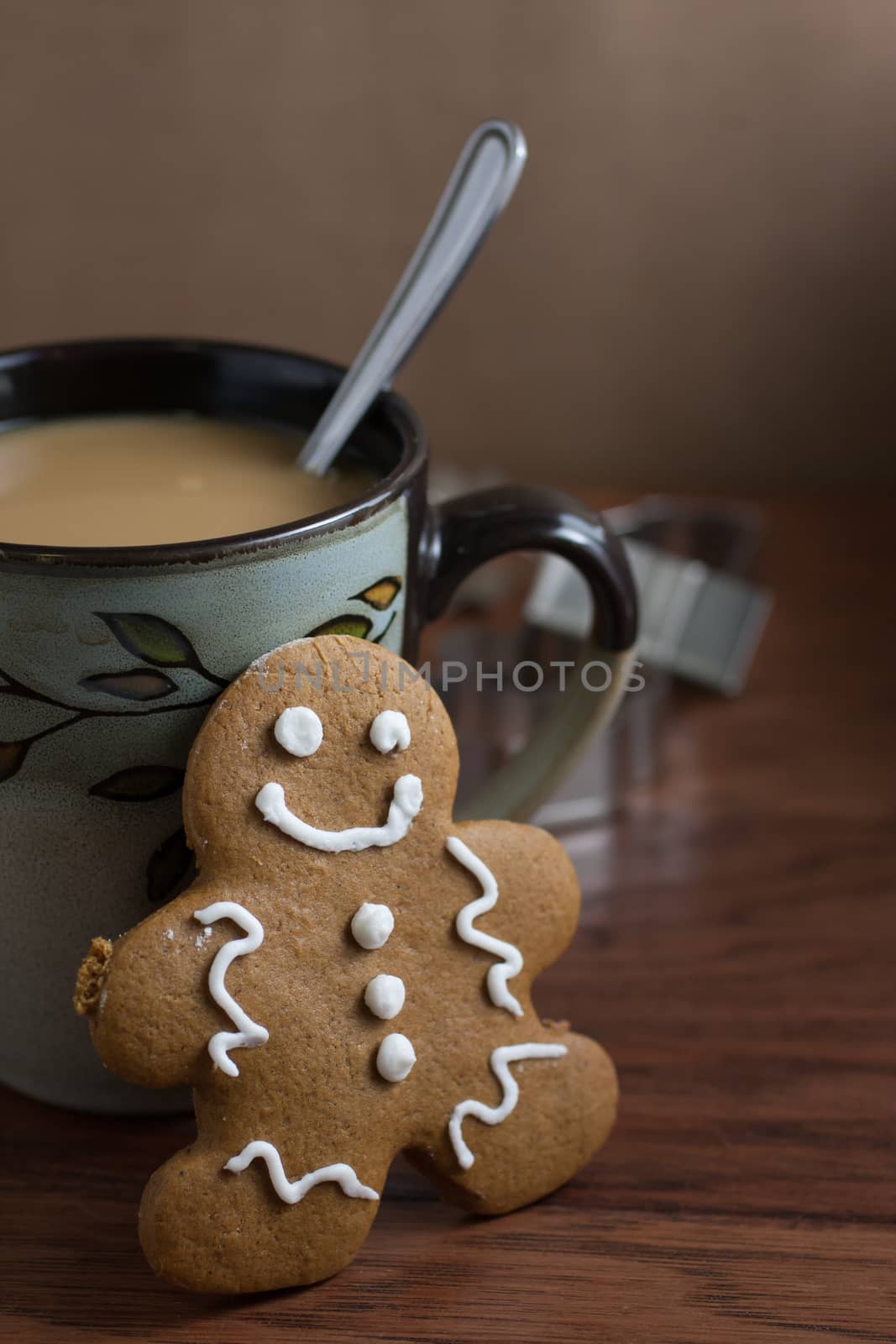 A gingerbread man cookie and a cup of fresh coffee on a wooden table.