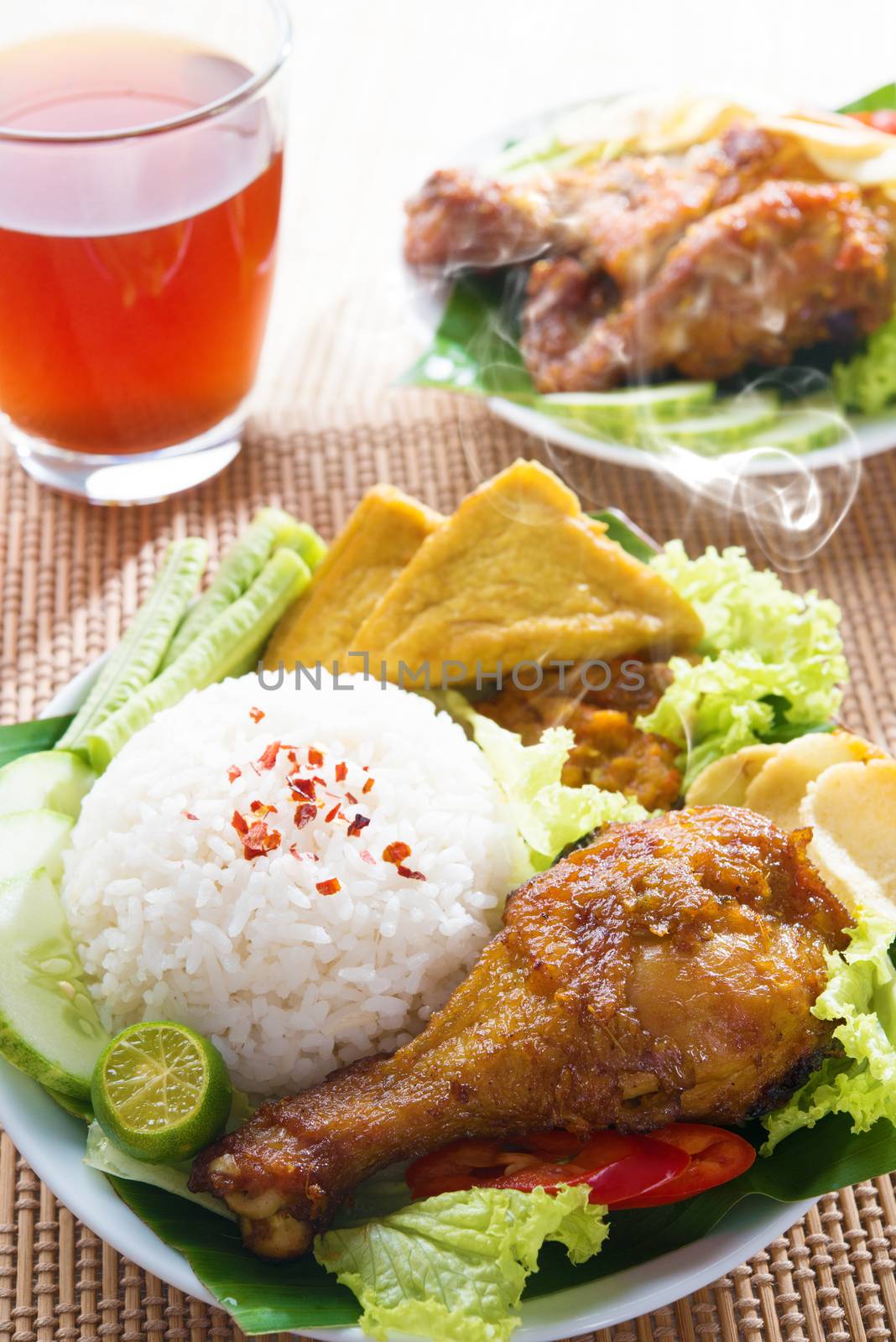 Popular Indonesian local food nasi ayam penyet, indonesian fried chicken rice. Fresh hot with steam smoke.