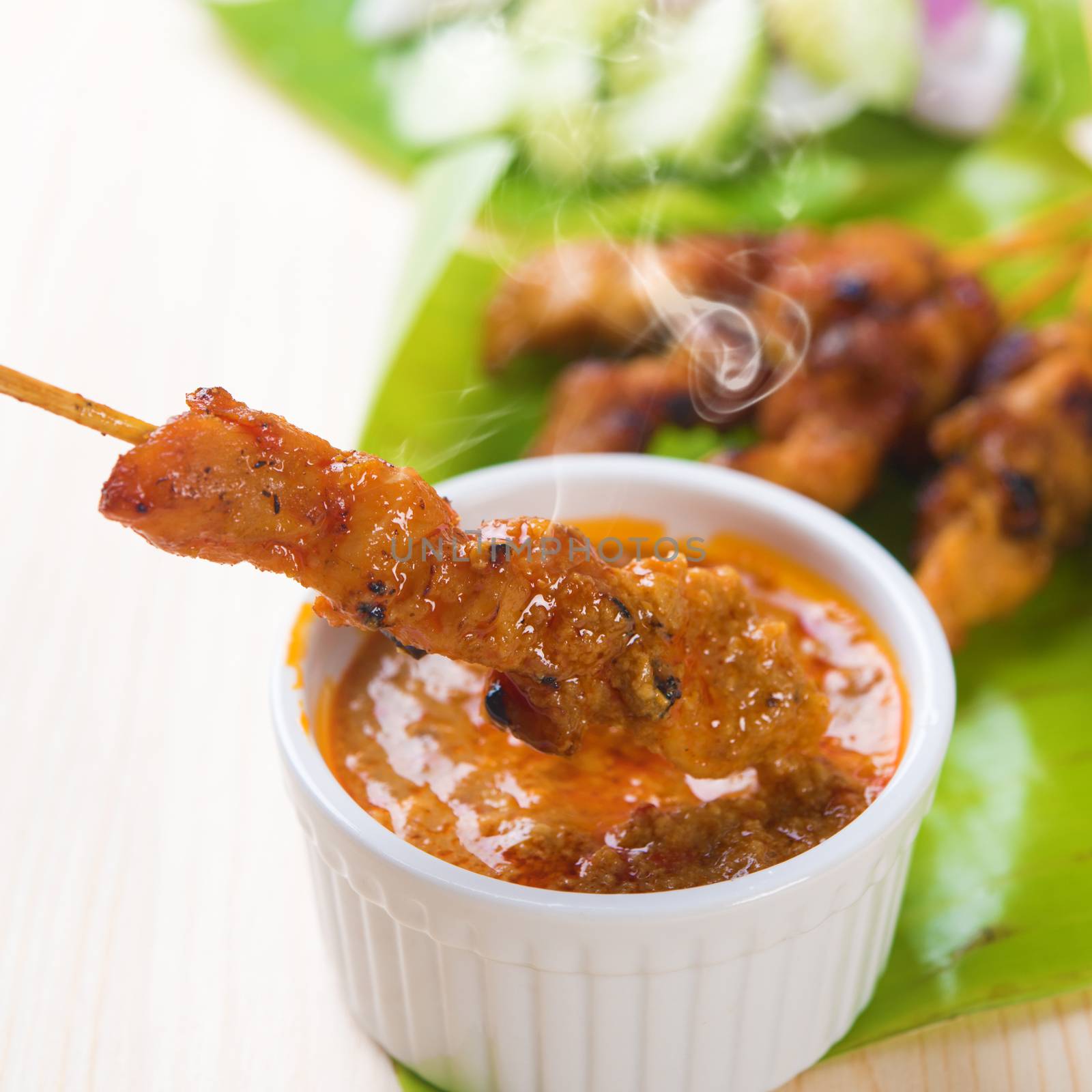 Delicious chicken sate or satay, skewered and grilled meat, served with peanut sauce. Fresh cooked with steamed and smoke. Hot and spicy Asian dish. 