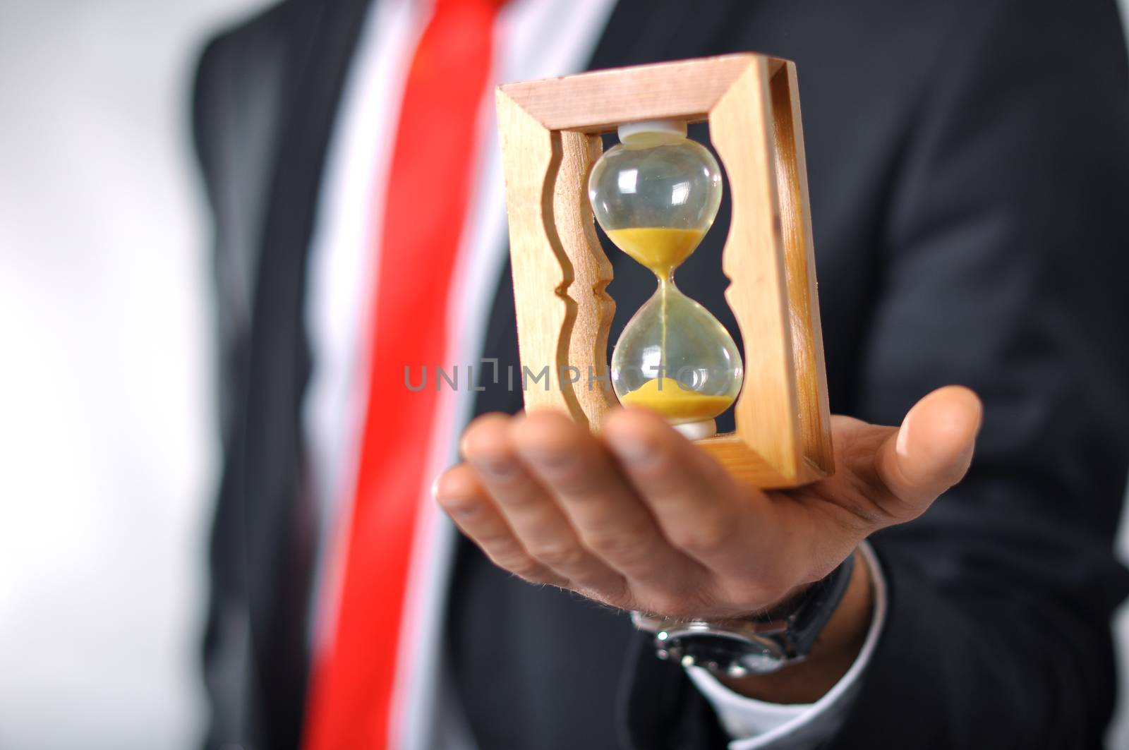 Man in a suit with tie holding an hourglass
