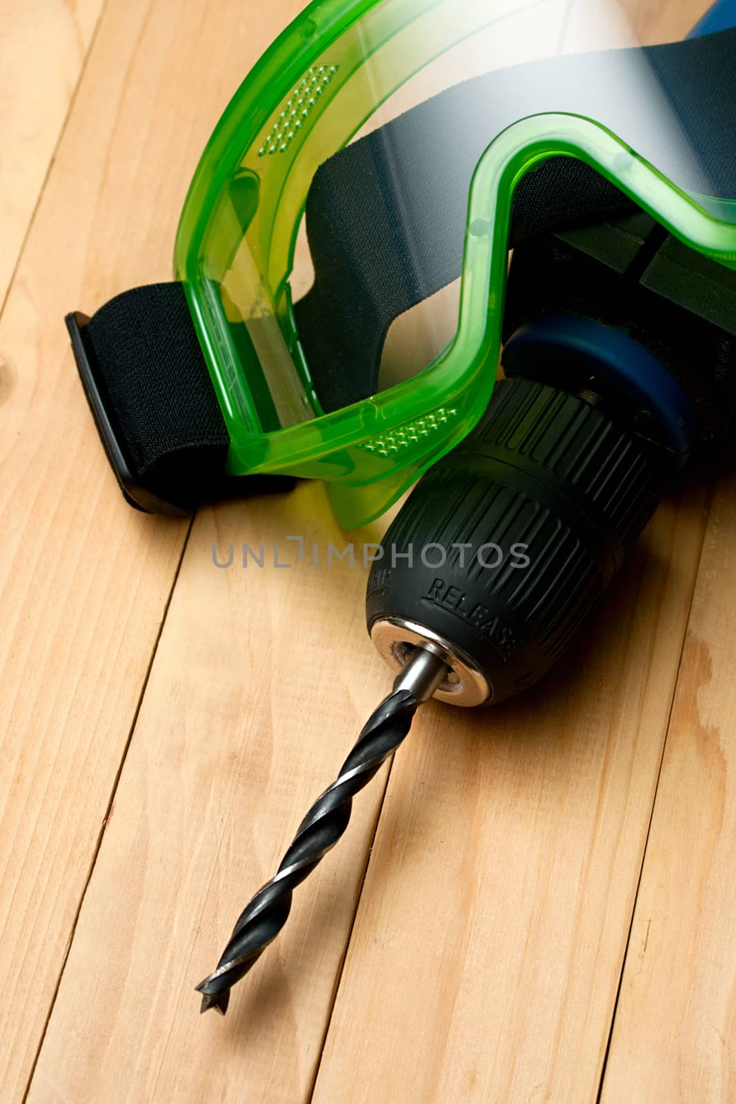 Handdrill and goggles on wooden background