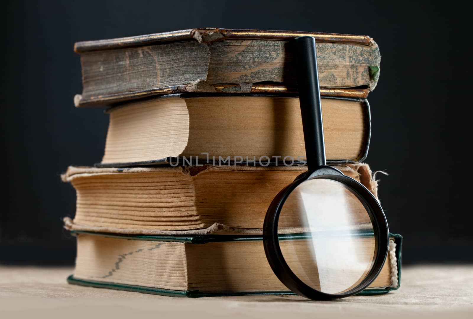 Pile of old books with magnifying glass by Garsya