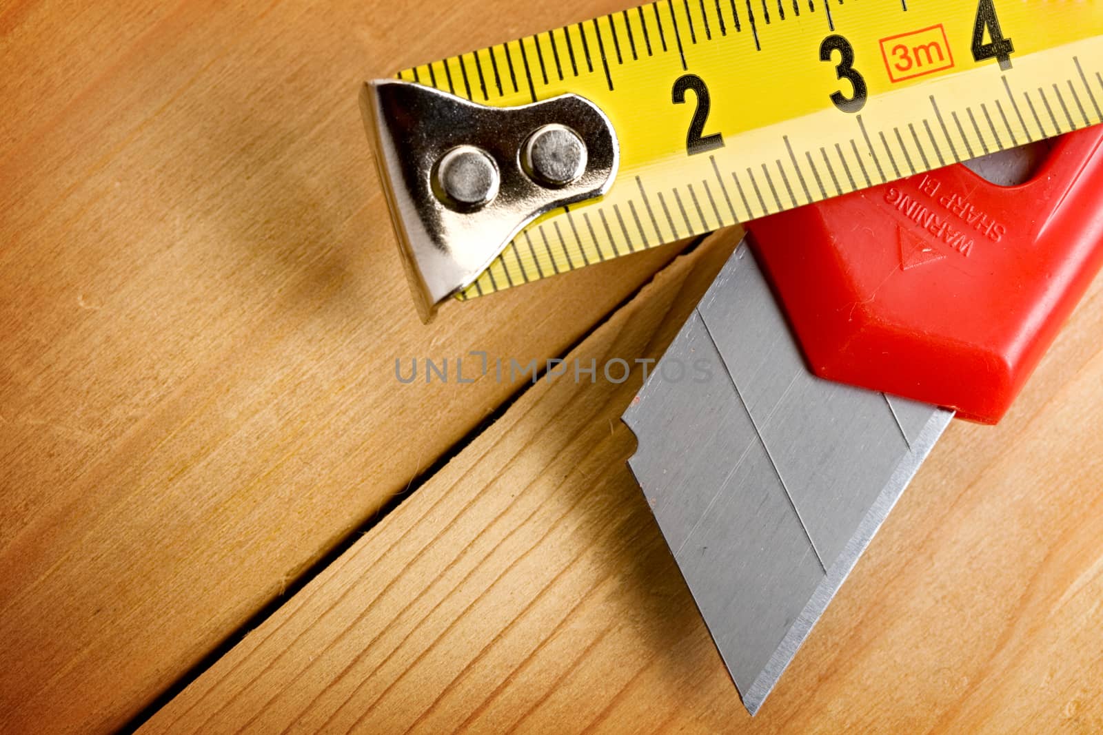Tape measure and knife on wooden background by Garsya