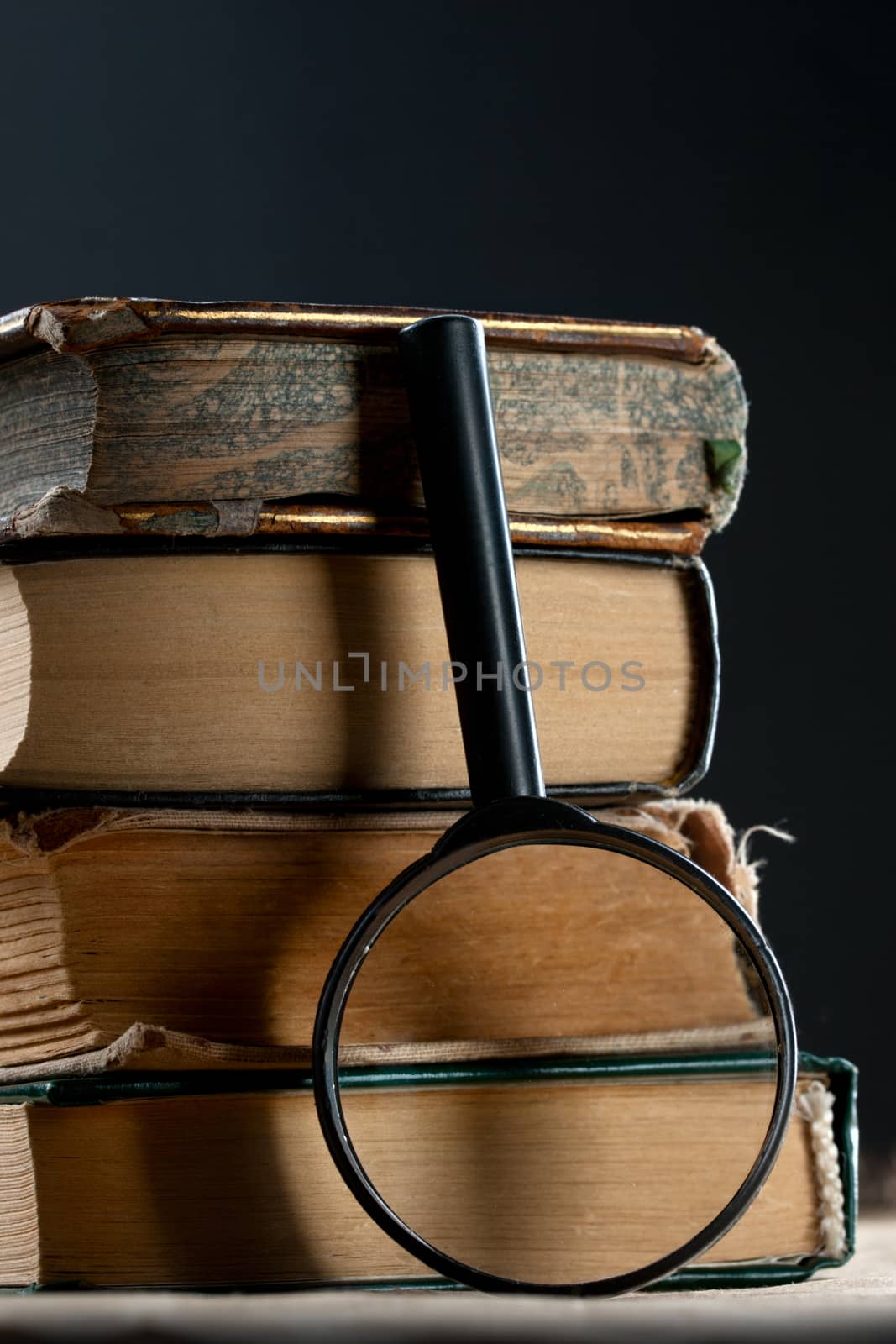 Pile of old books with magnifying glass by Garsya