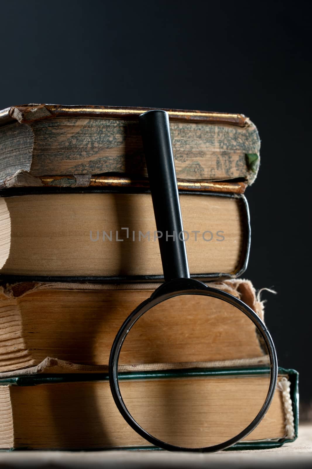 Pile of old books with magnifying glass