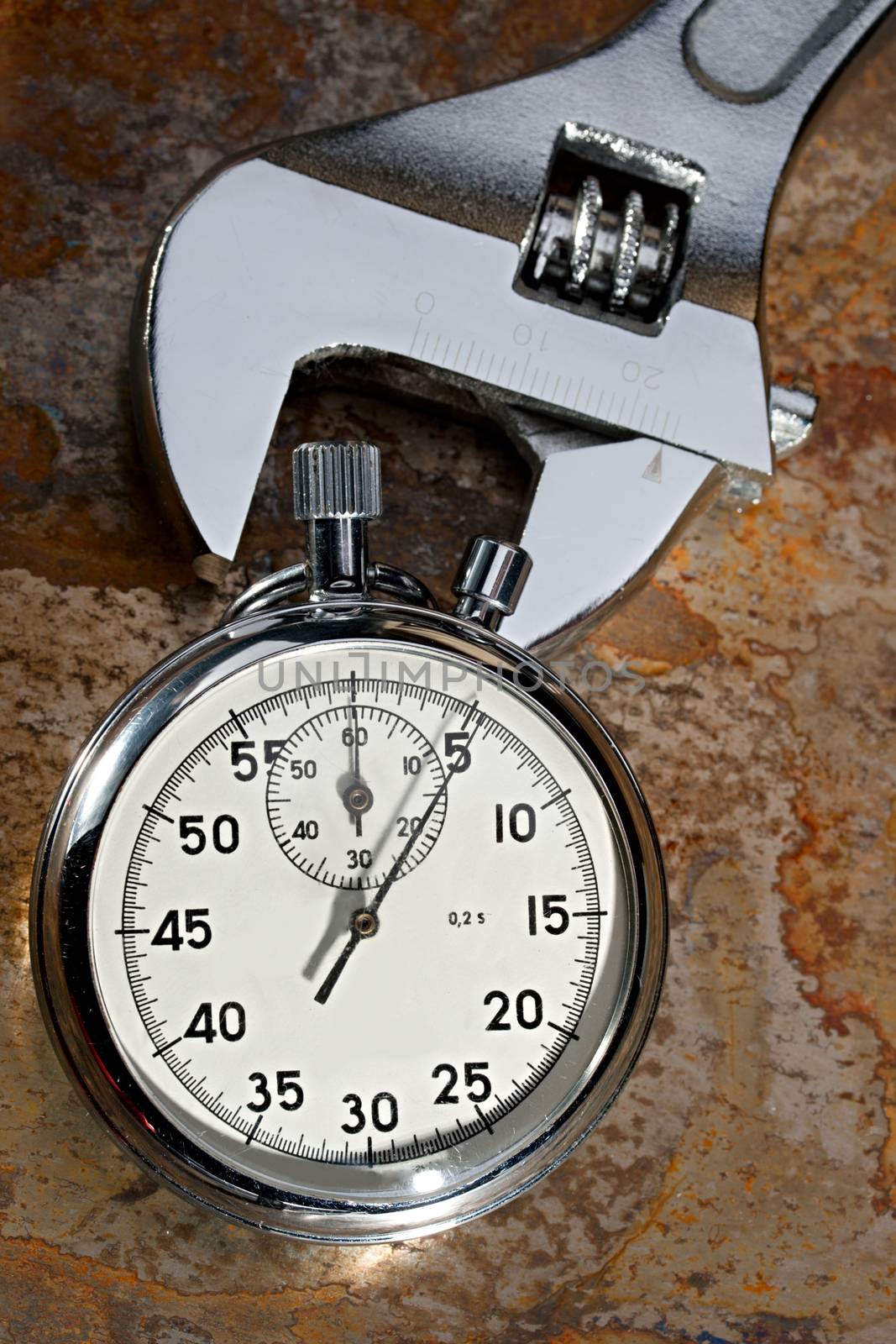 Spanner and stopwatch on the rusty plate by Garsya