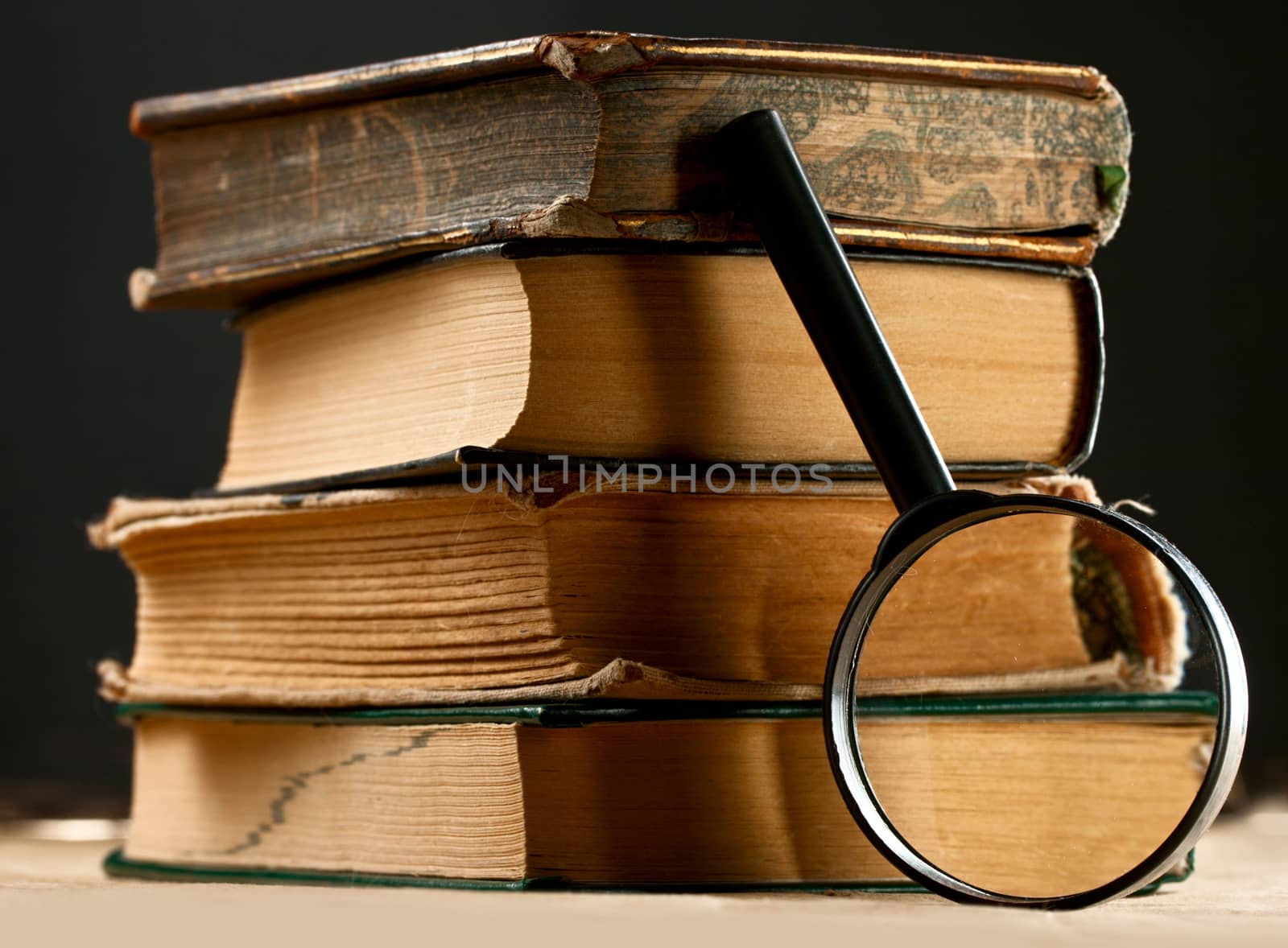 Pile of old books with magnifying glass