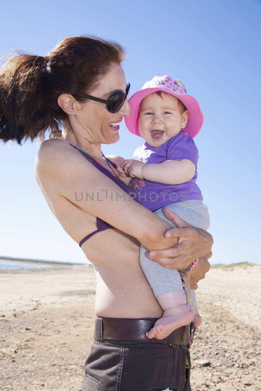 portrait of mother and baby hugging at the beach