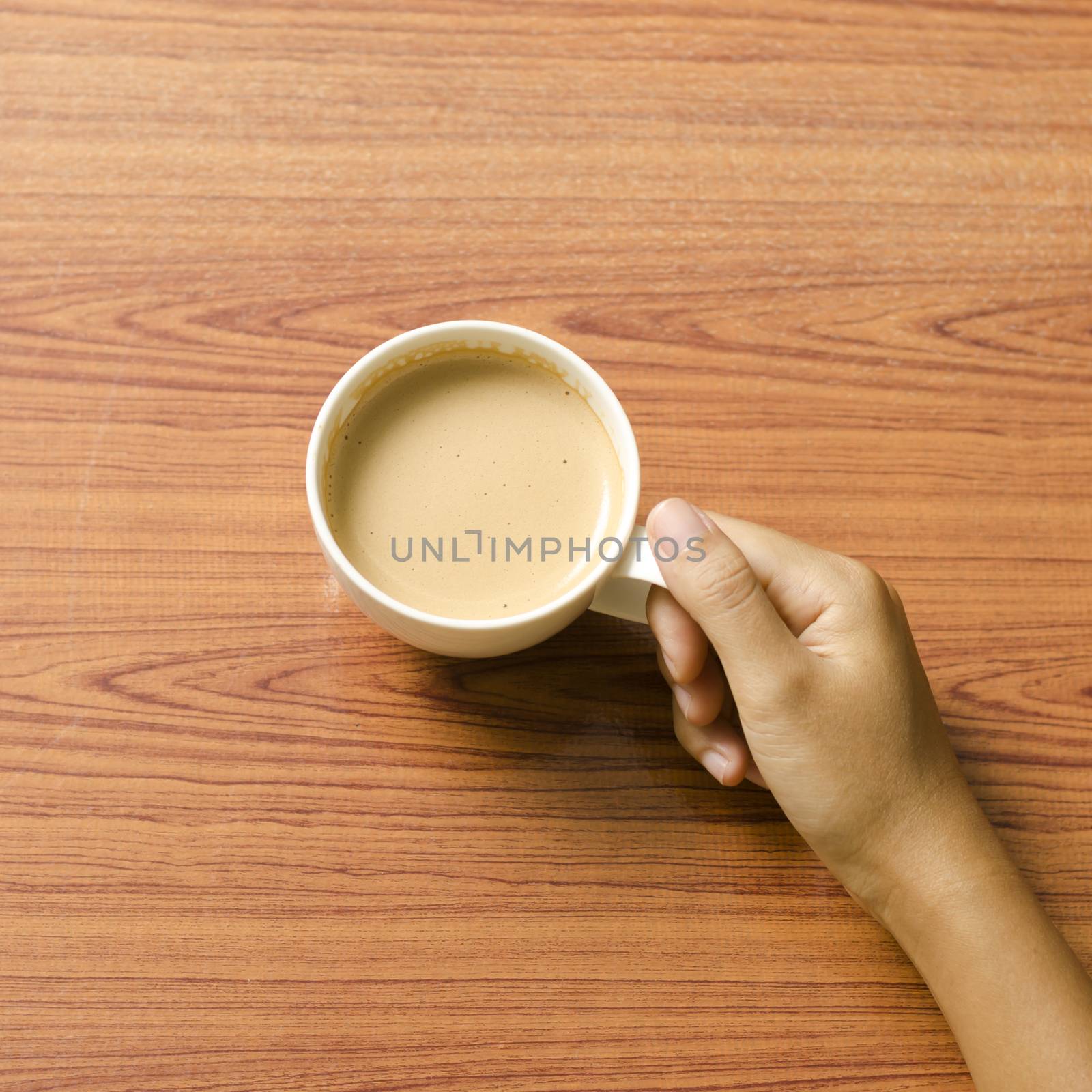 woman hand holding coffee cup on wood table background