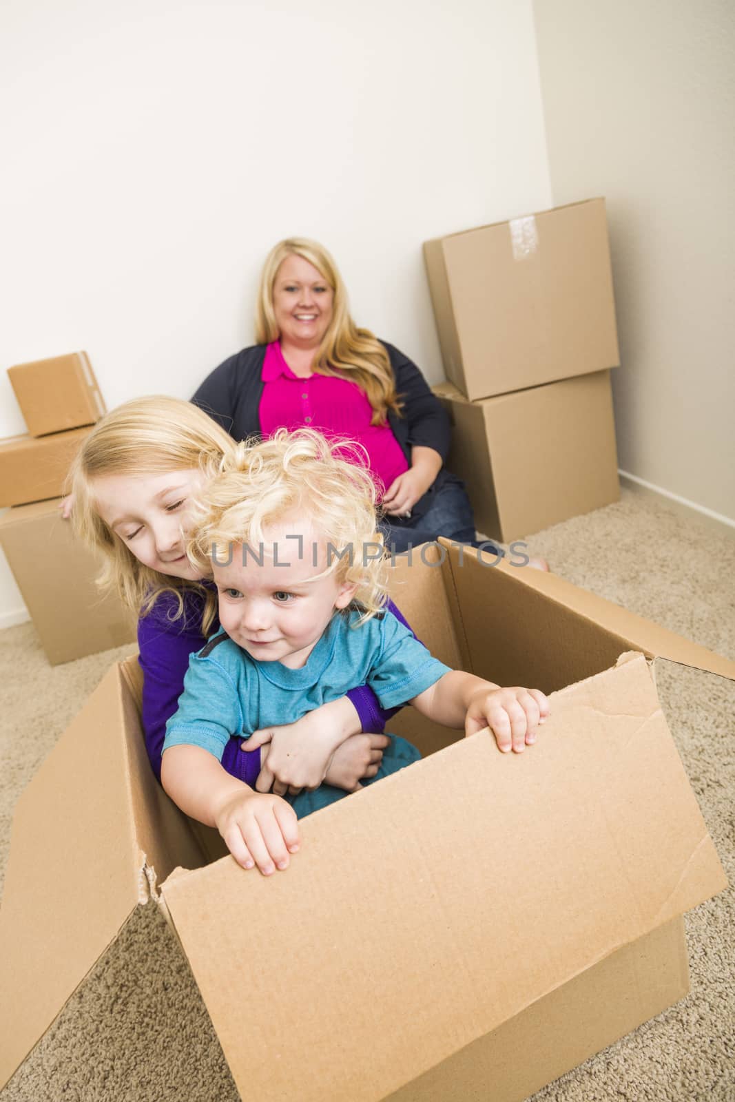 Young Family In Empty Room Playing With Moving Boxes by Feverpitched