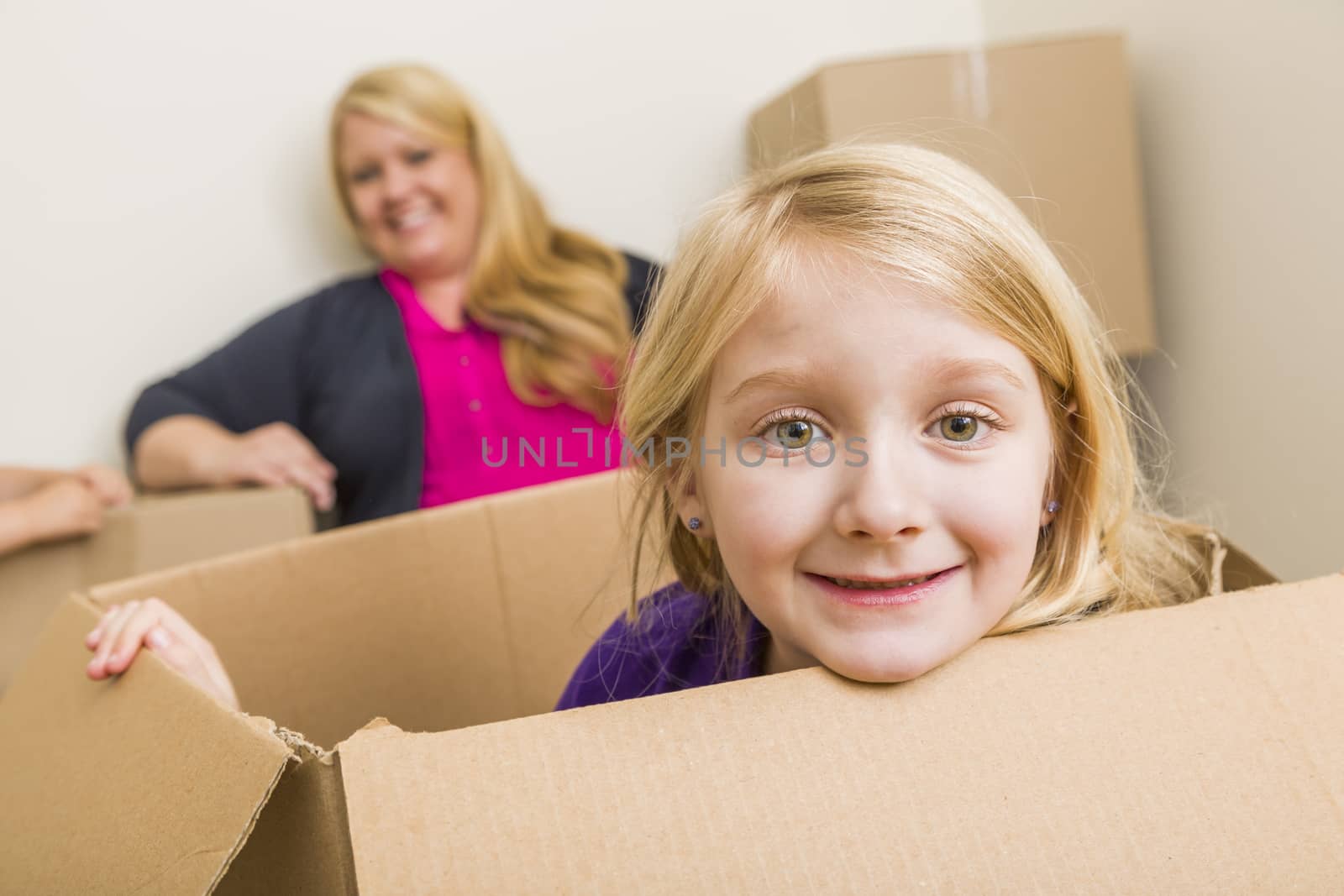 Happy Young Mother and Daughter Having Fun With Moving Boxes.