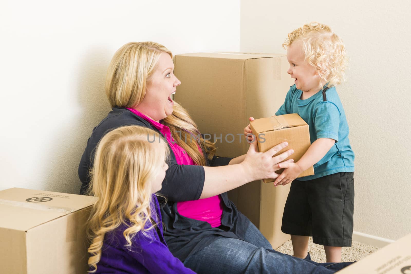 Young Family In Empty Room Playing With Moving Boxes by Feverpitched