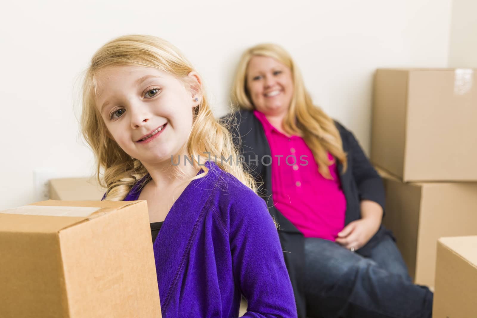 Young Mother and Daughter In Empty Room With Moving Boxes by Feverpitched