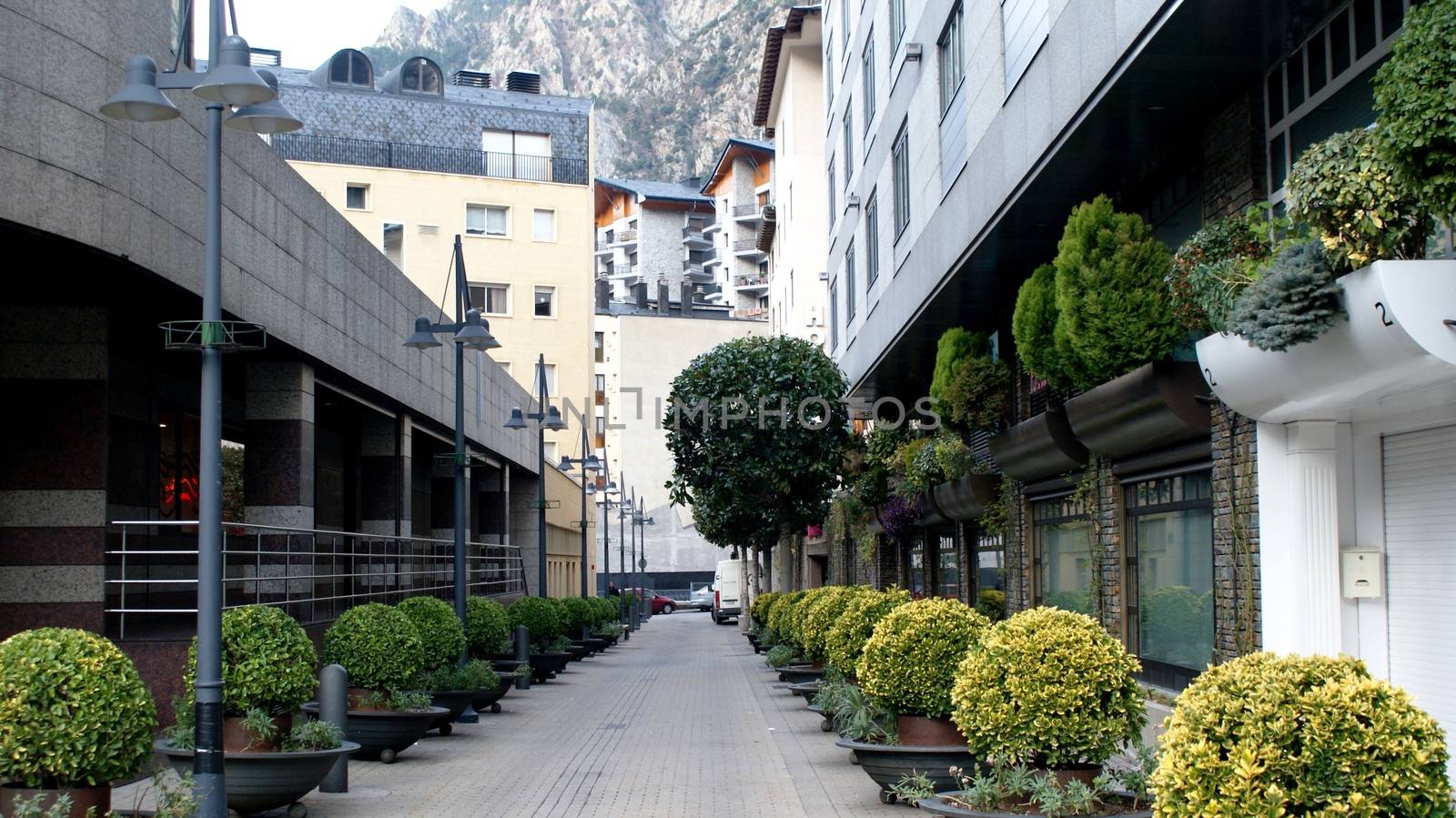 Clear street in Andorra-la-Vella with buildings and bushes.