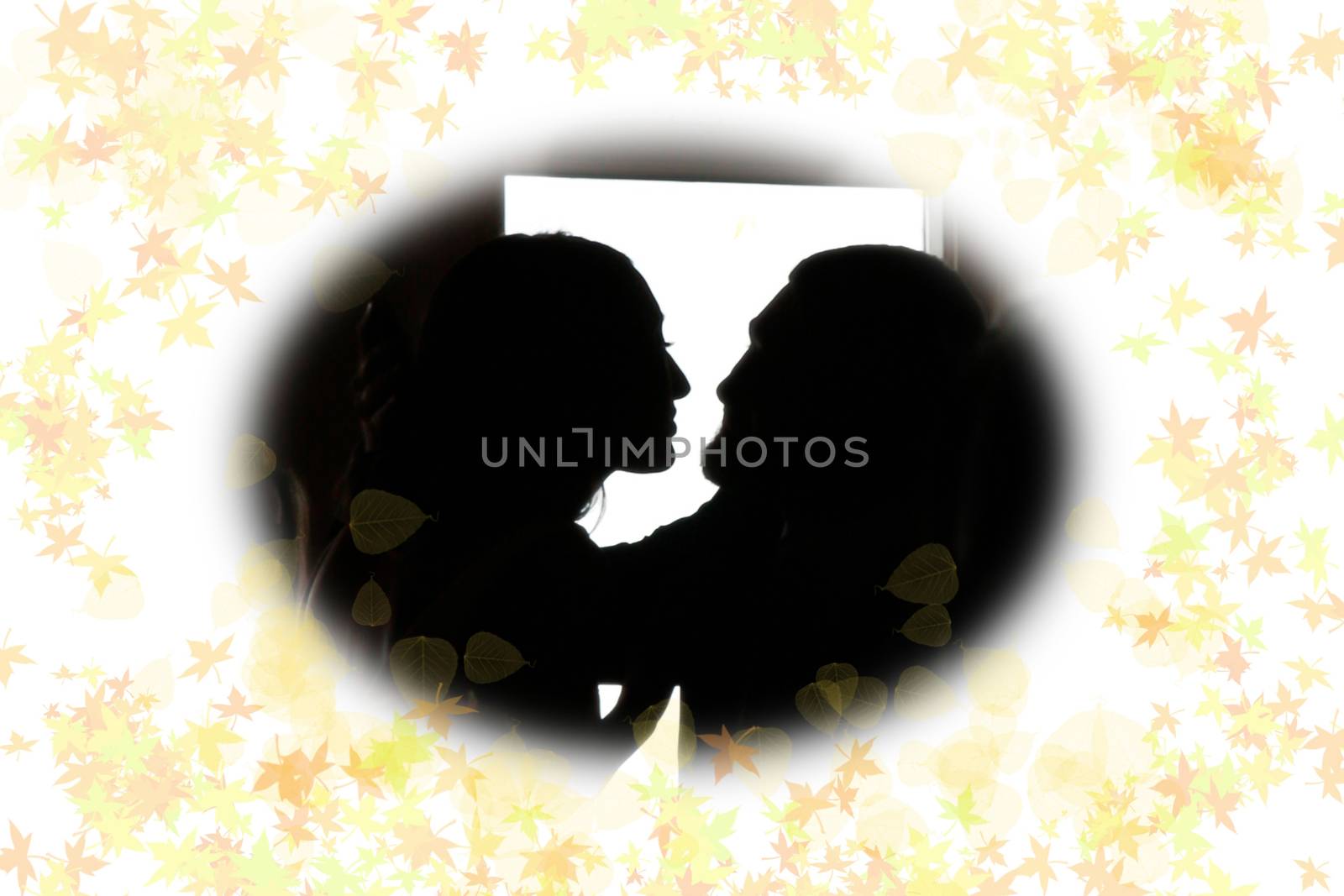 young loving couple holding each other in silhouette with leafy frame gazing into each others eyes