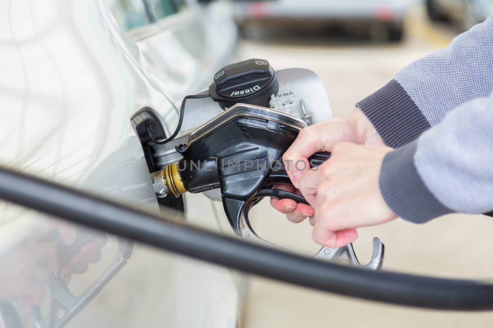 Petrol or gasoline being pumped into a motor vehicle car. Closeup of man pumping gasoline fuel in car at gas station.