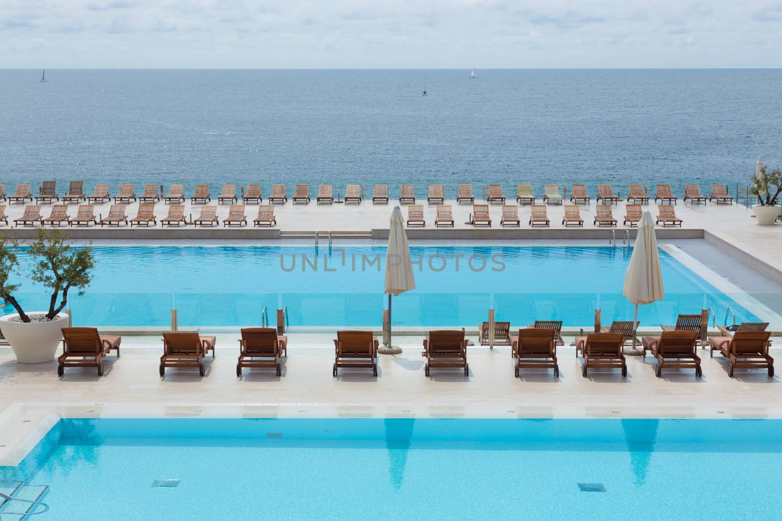 Turquoise swimming pool with modern wooden sunbeds