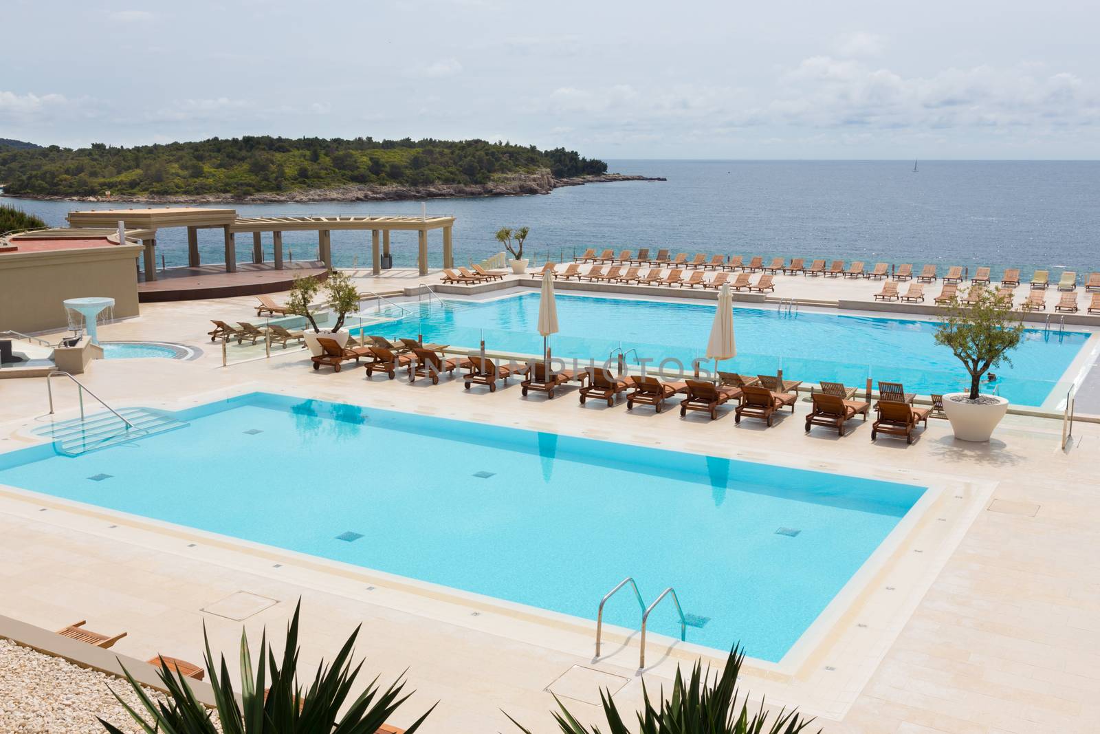 Turquoise swimming pool with modern wooden sunbeds