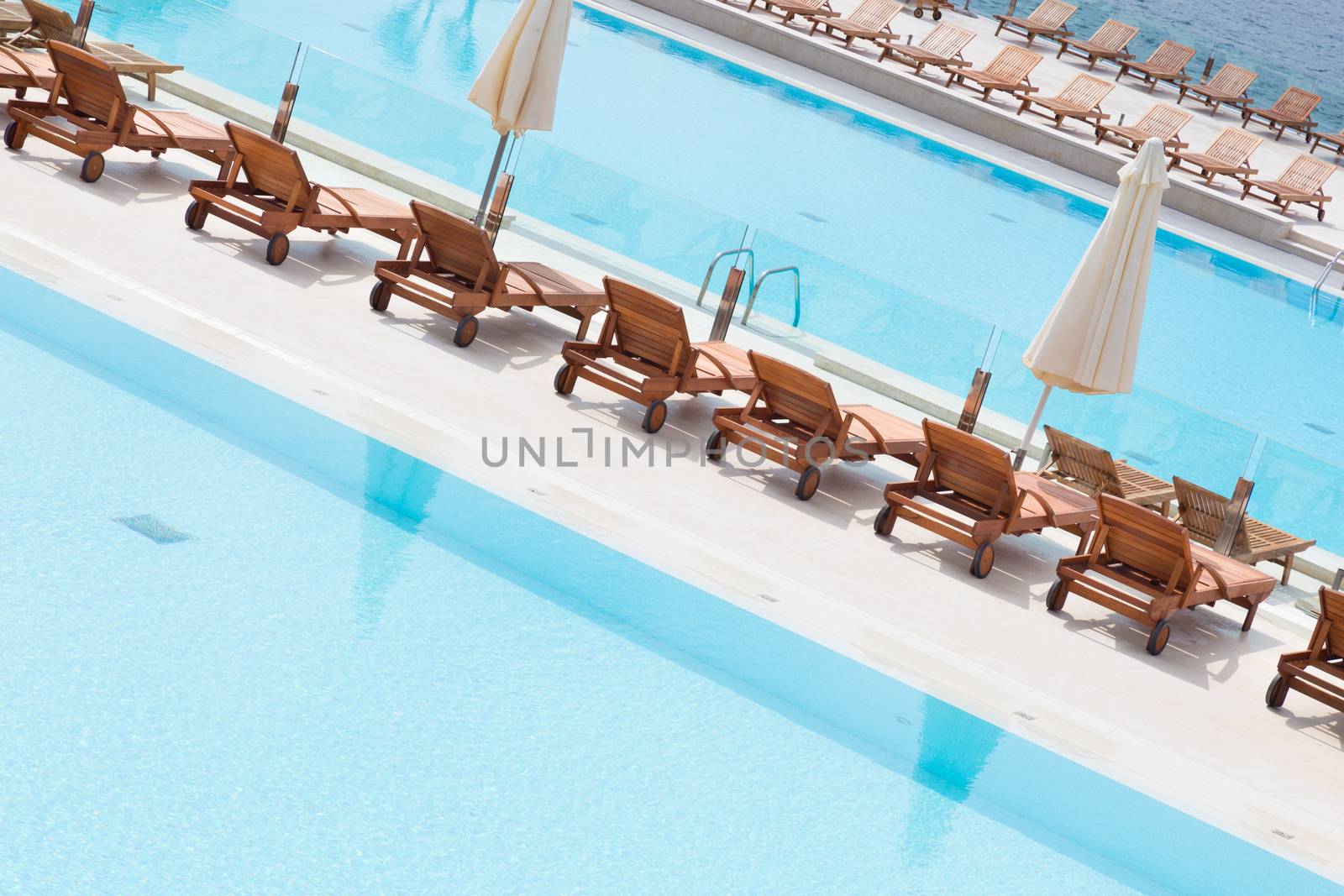 Turquoise swimming pool with modern wooden sunbeds