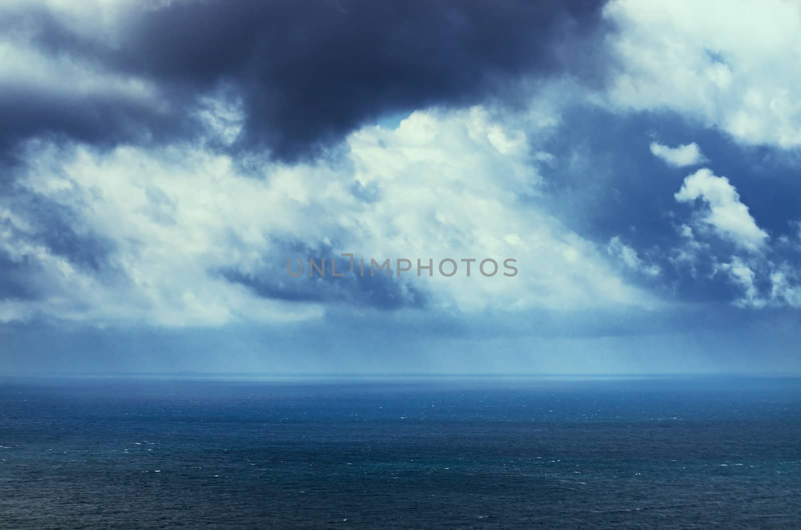 Cloudy blue sky above a blue surface of the sea