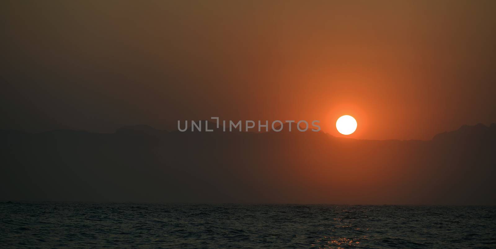 orange sunset at the ocean with mountains silhouettes. South Africa