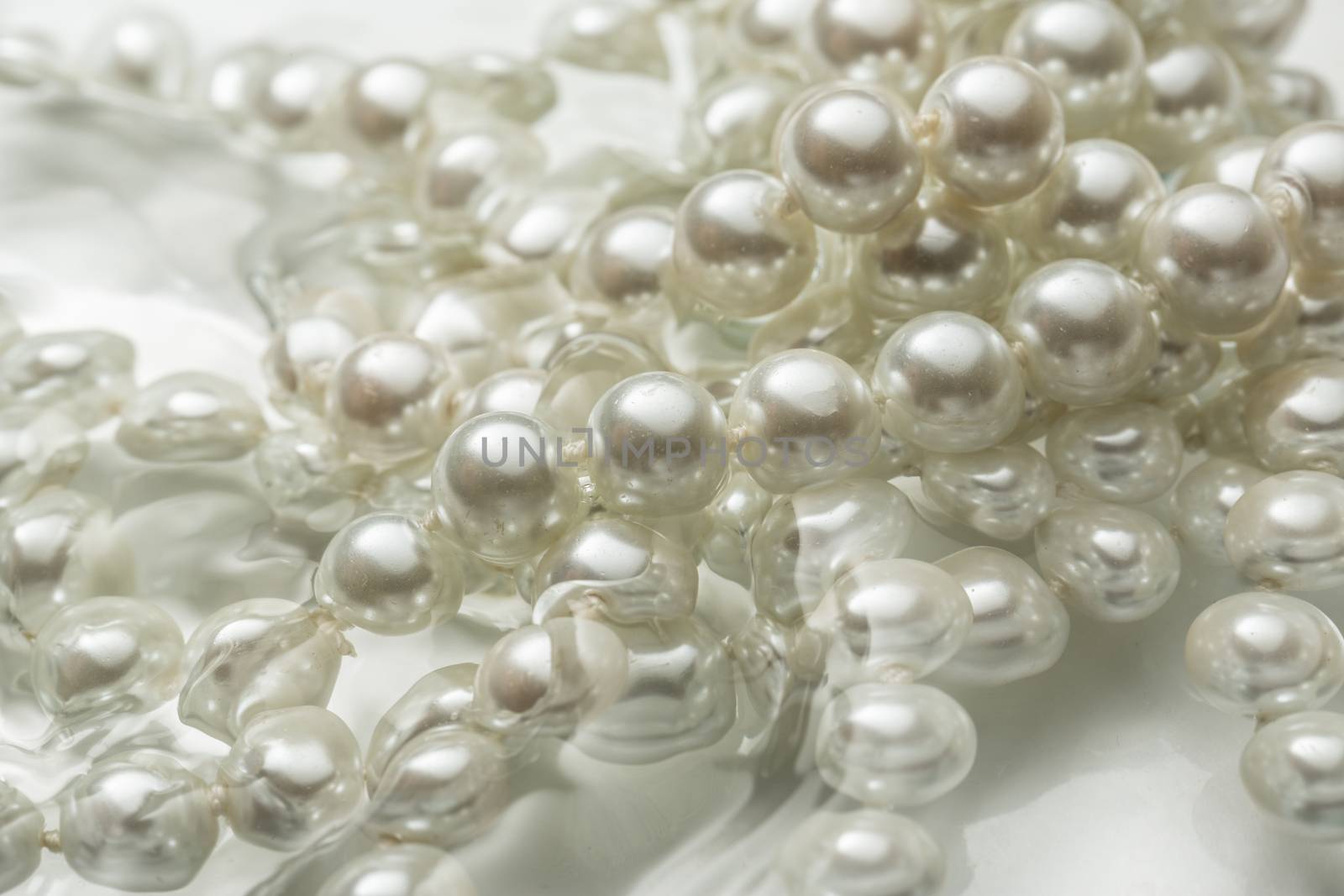 Shining string of white pearl in water by Garsya