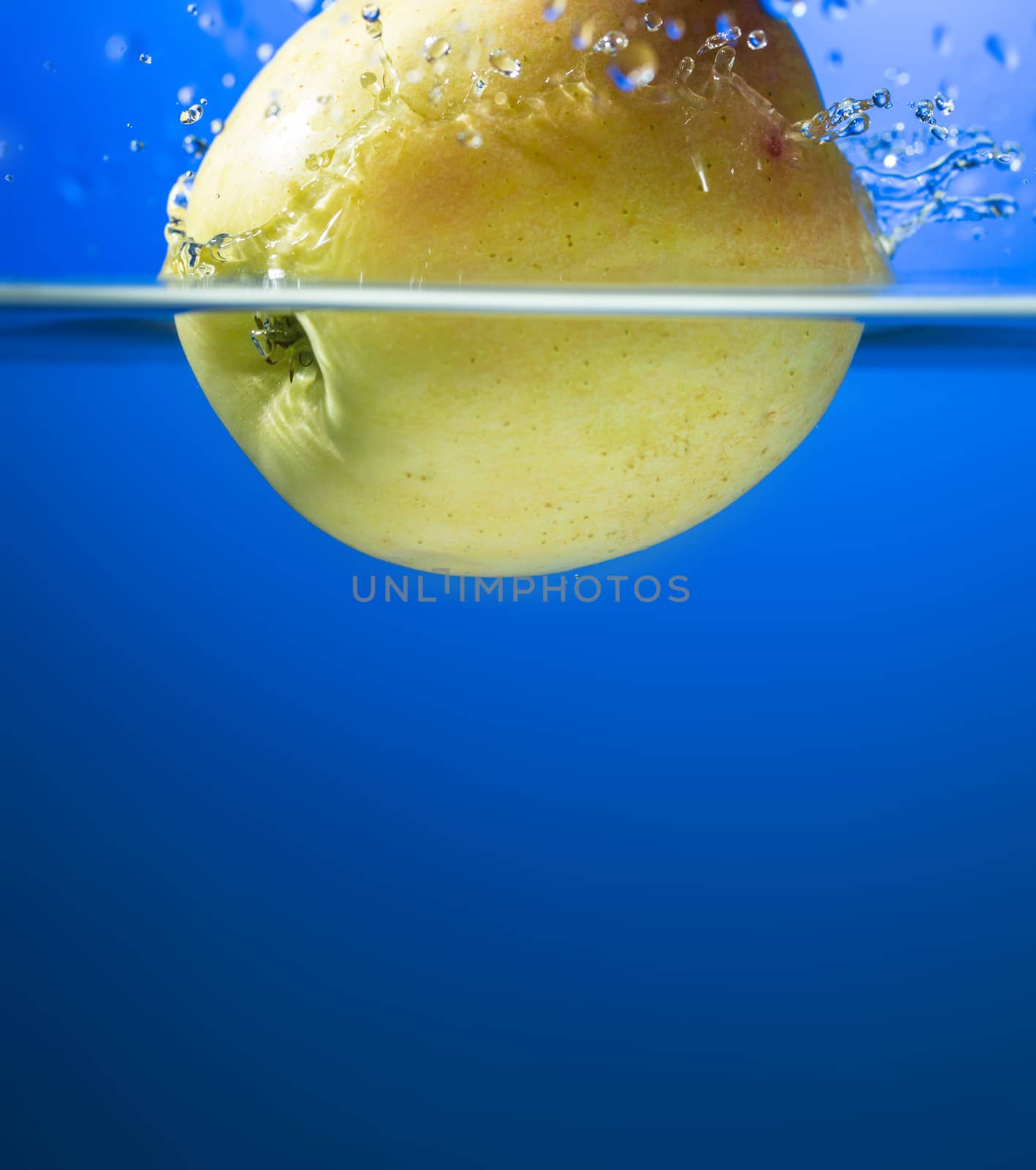 Yellow apple in water splash