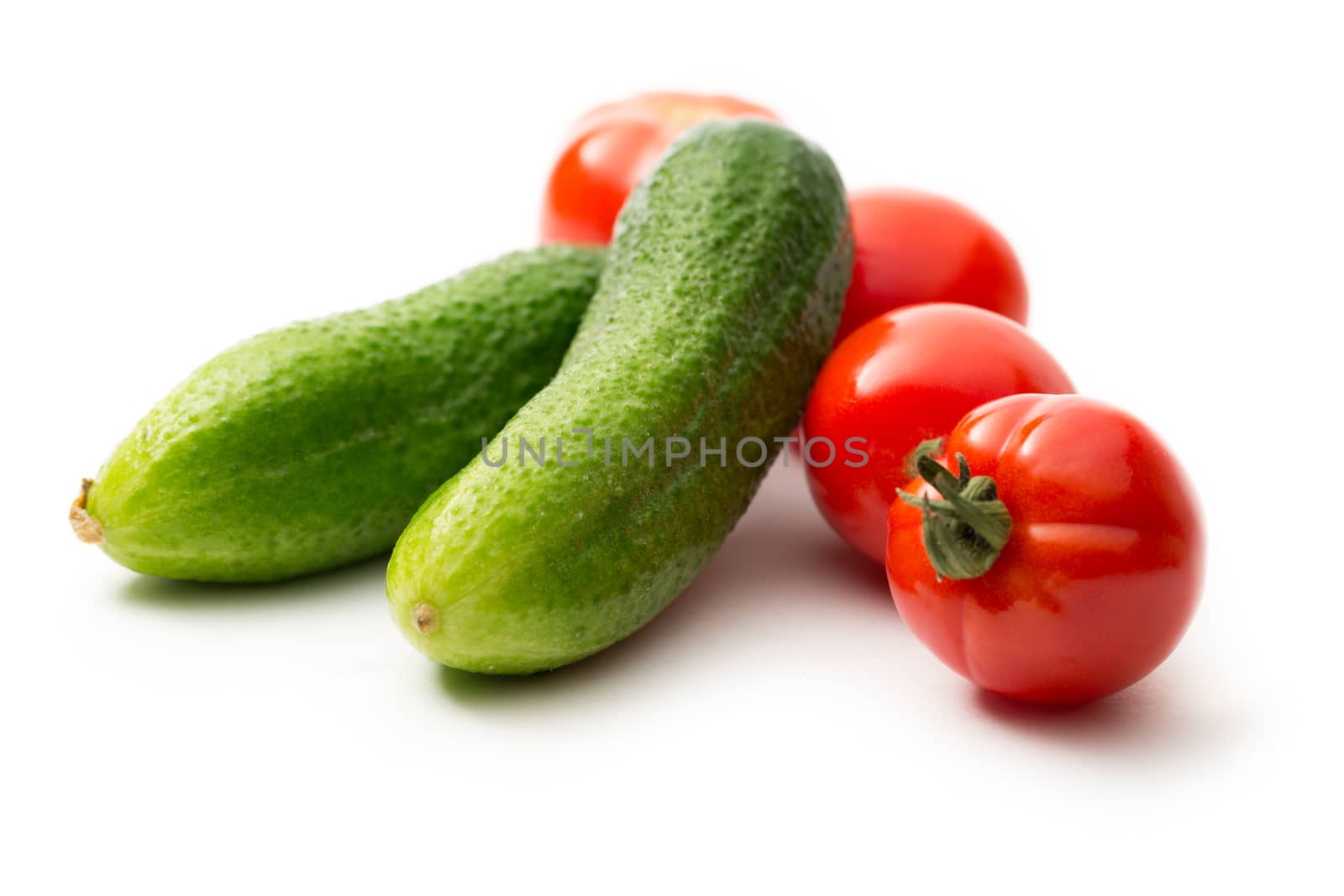 Fresh cucumbers and tomatoes on white by Garsya