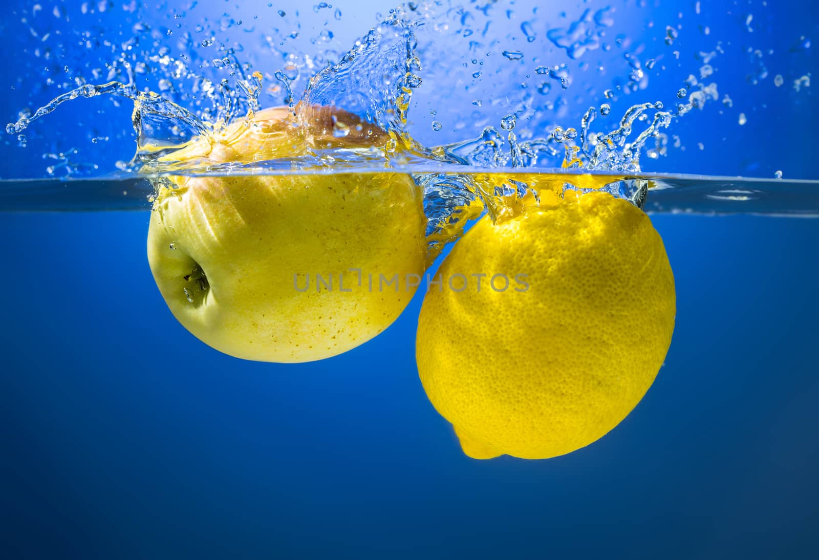 Yellow lemon and apple in water splash