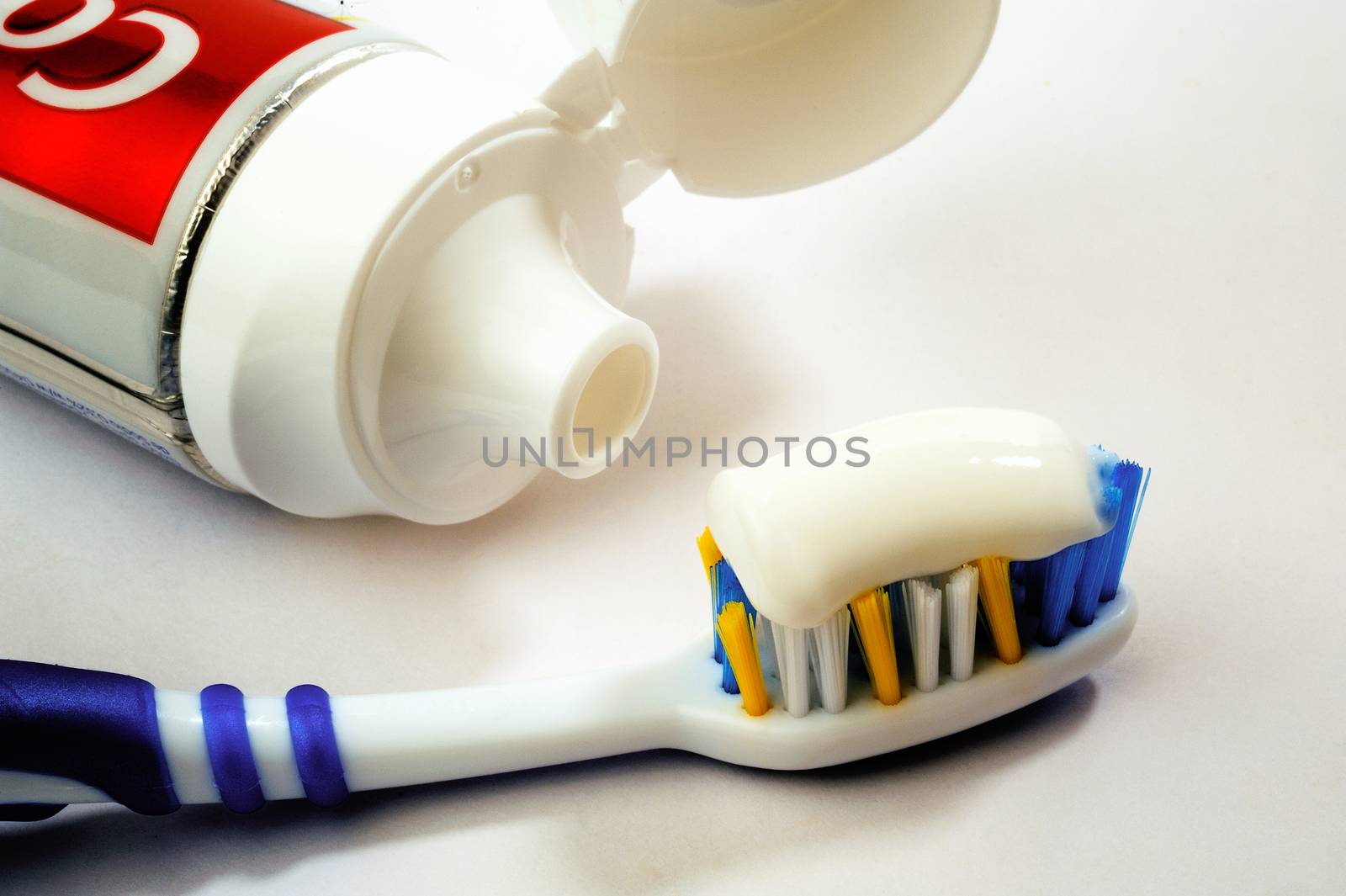 Entire tube of toothpaste with a toothbrush close-up on white background