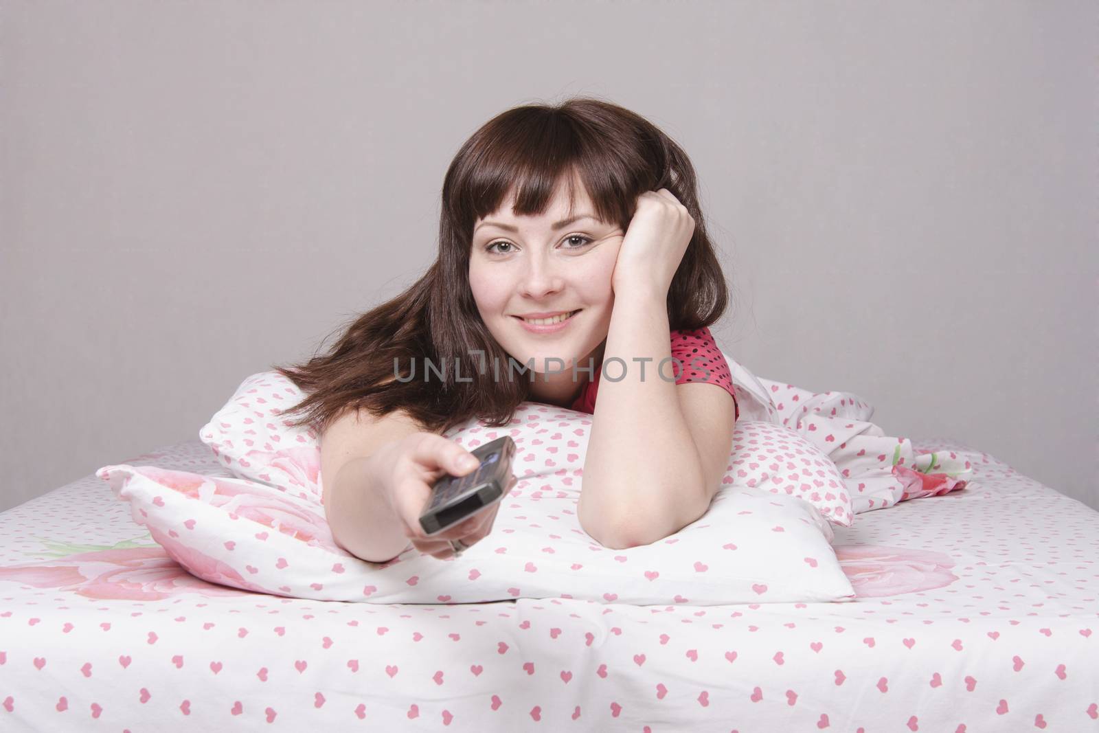 The girl lying in bed and watching TV
