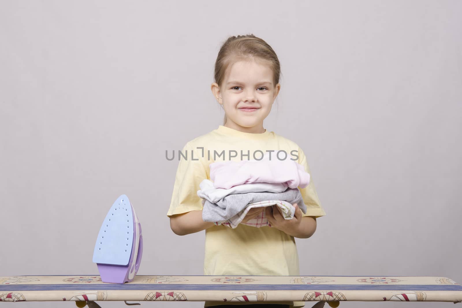A five year old girl playing in a housewife, and stroking things iron