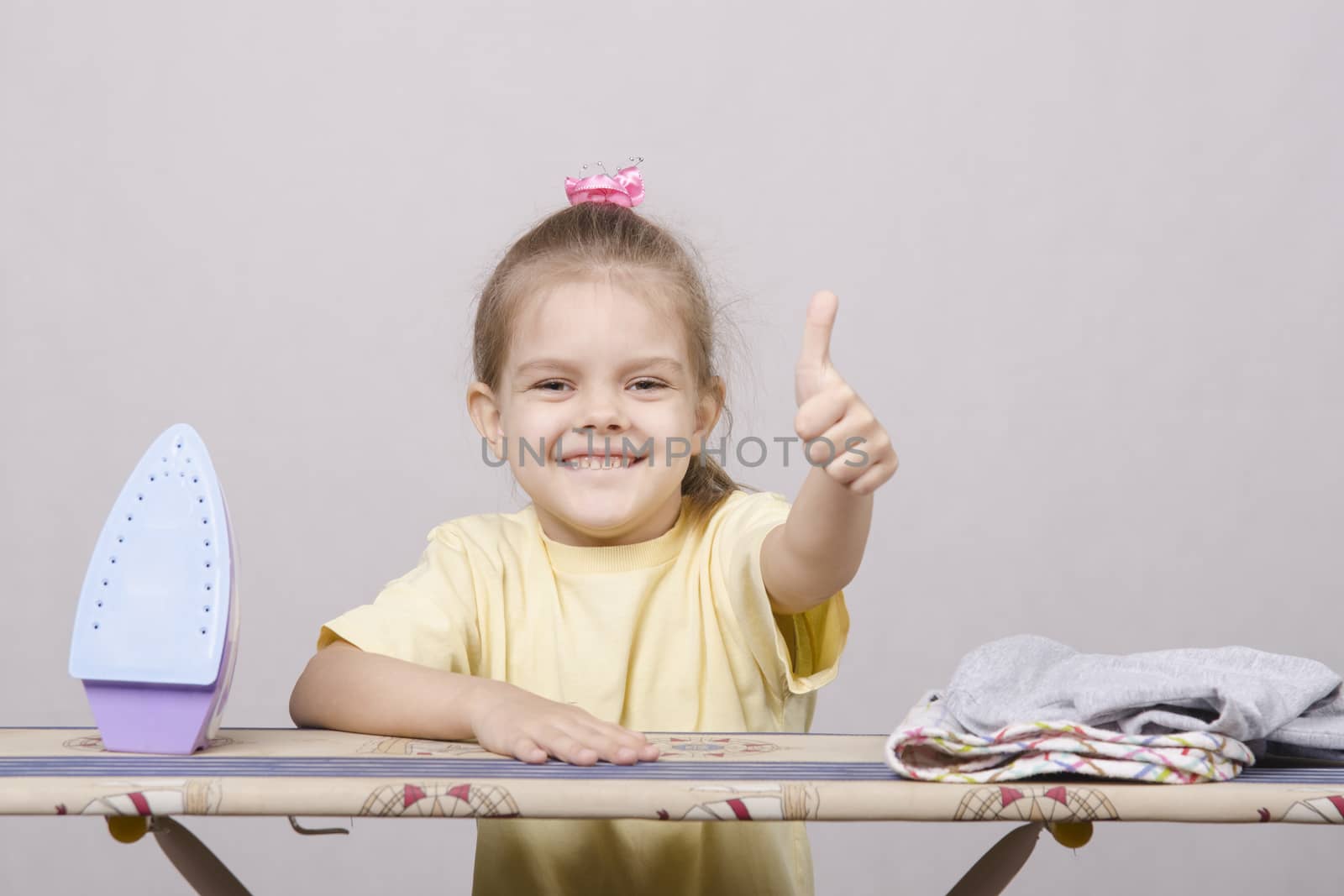 A five year old girl playing in a housewife, and stroking things iron