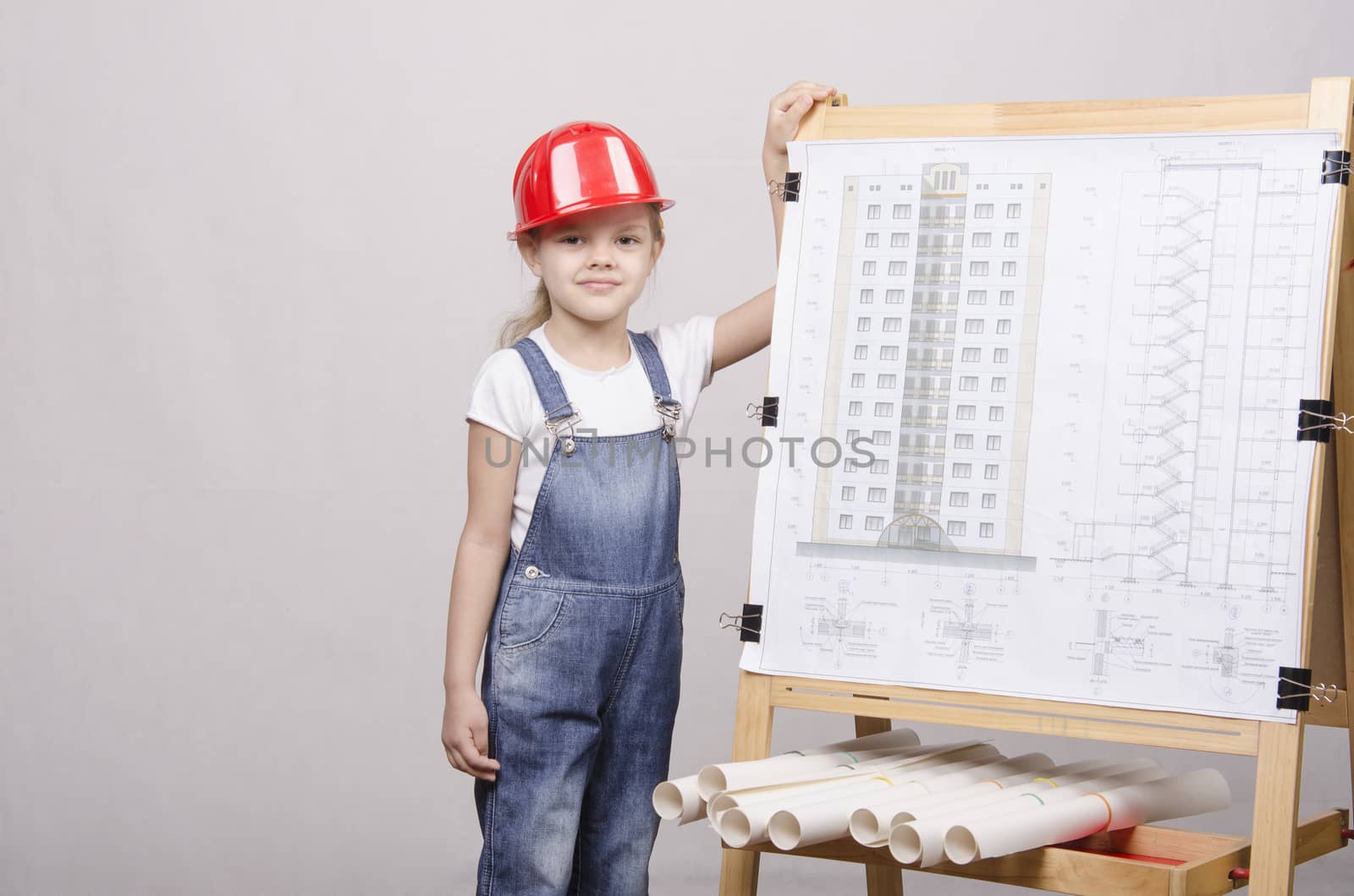 Girl Builder, architect, stands at the blackboard with the drawing of the building