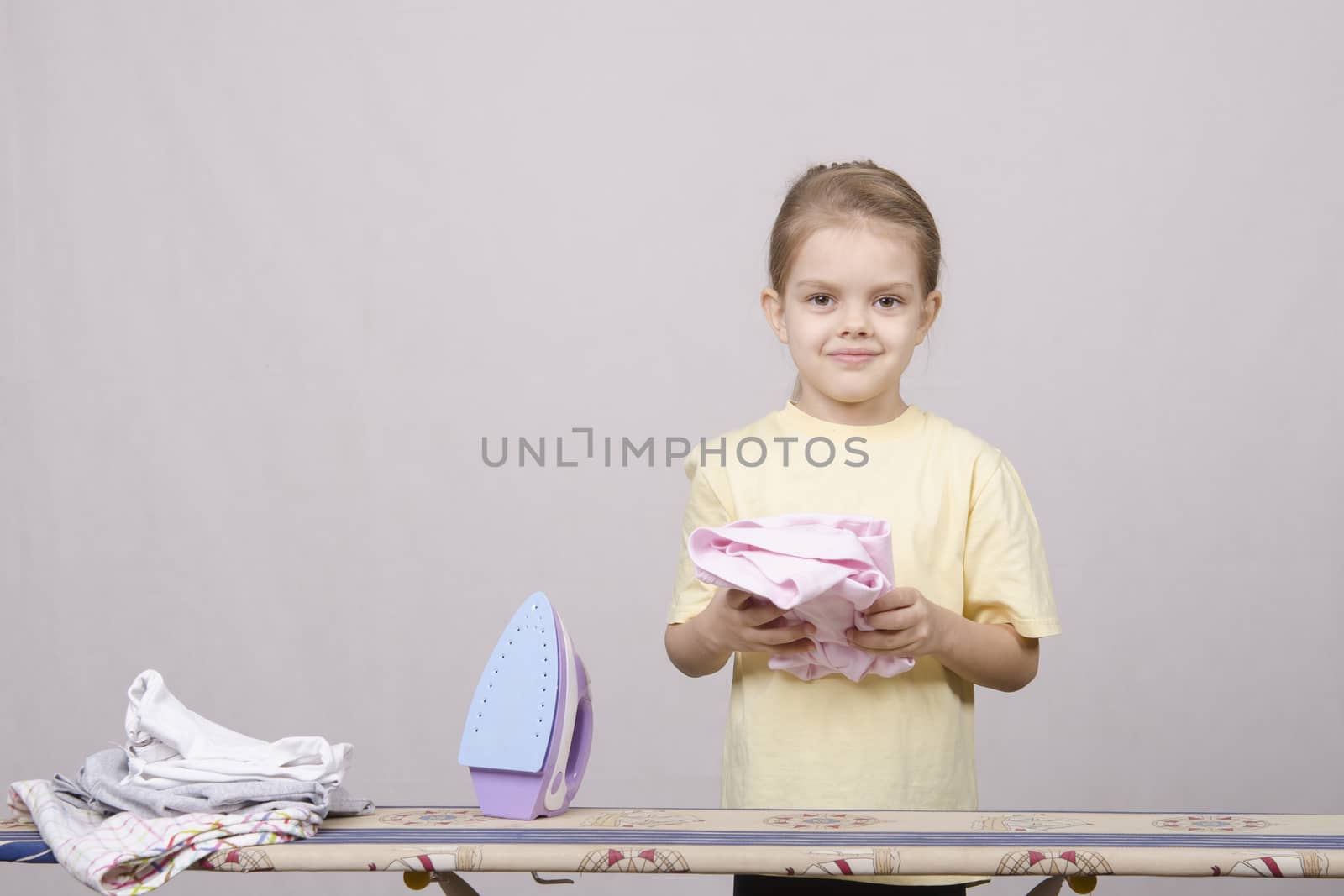 A five year old girl playing in a housewife, and stroking things iron