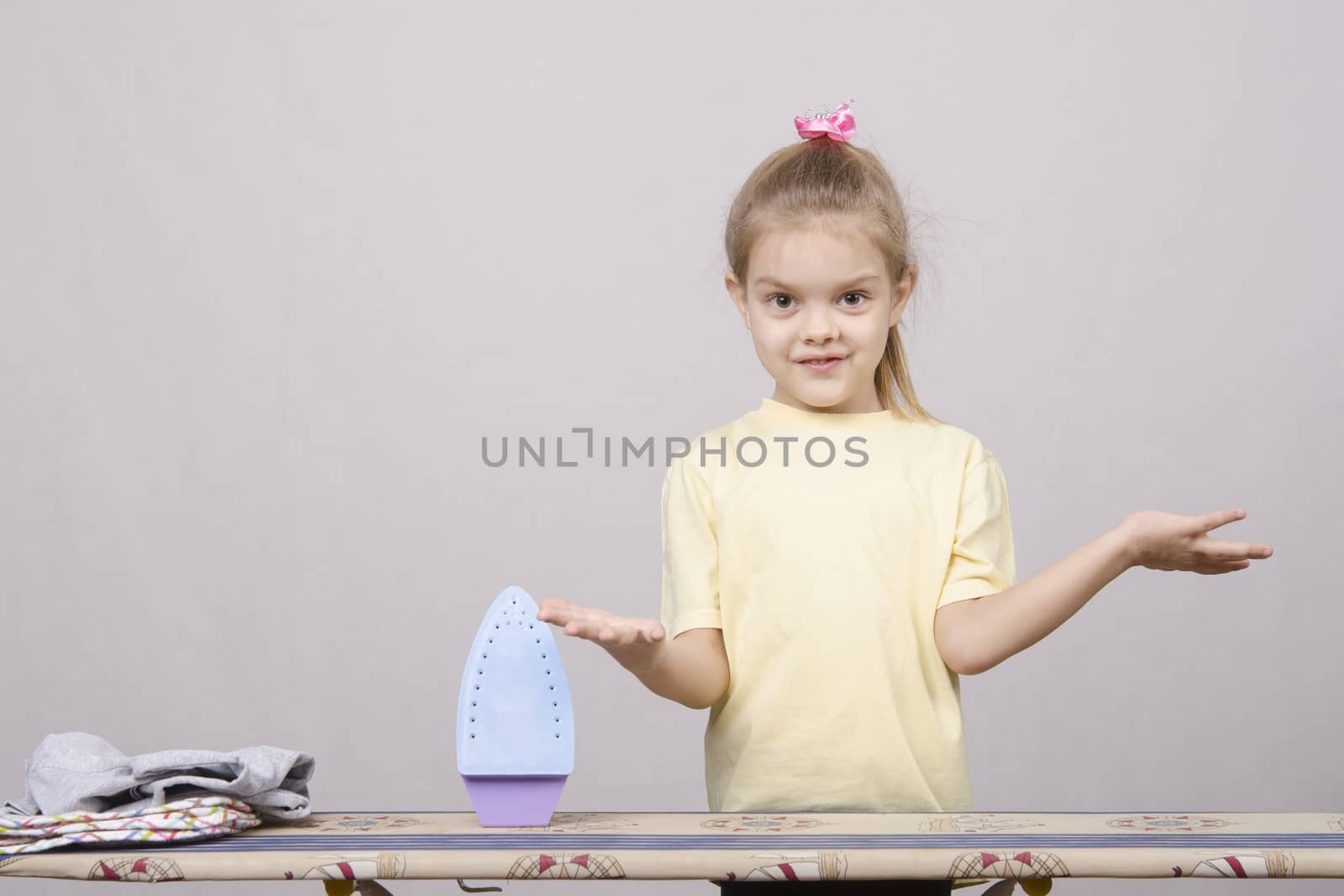 A five year old girl playing in a housewife, and stroking things iron