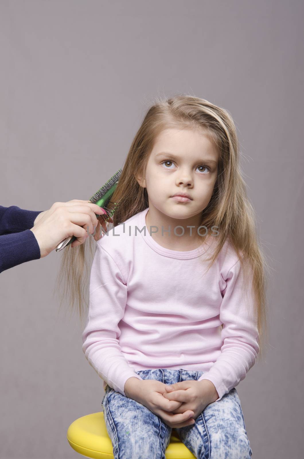 Hairdresser brushing her long hair five year old girl