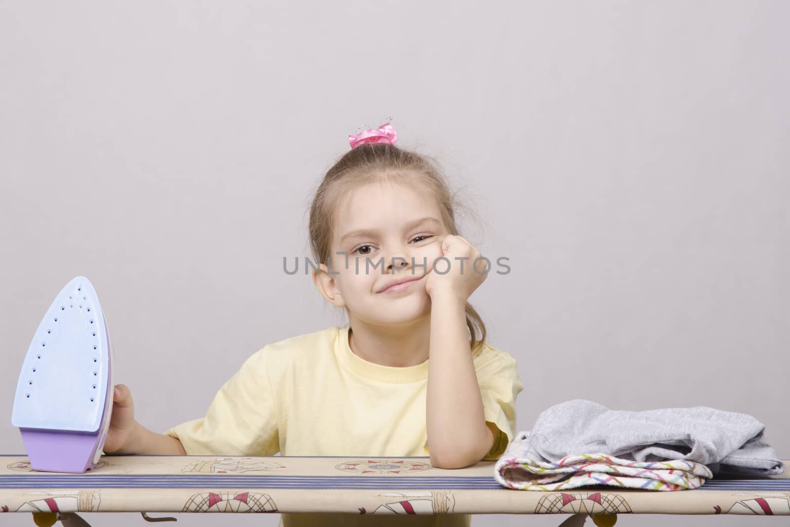 A five year old girl playing in a housewife, and stroking things iron