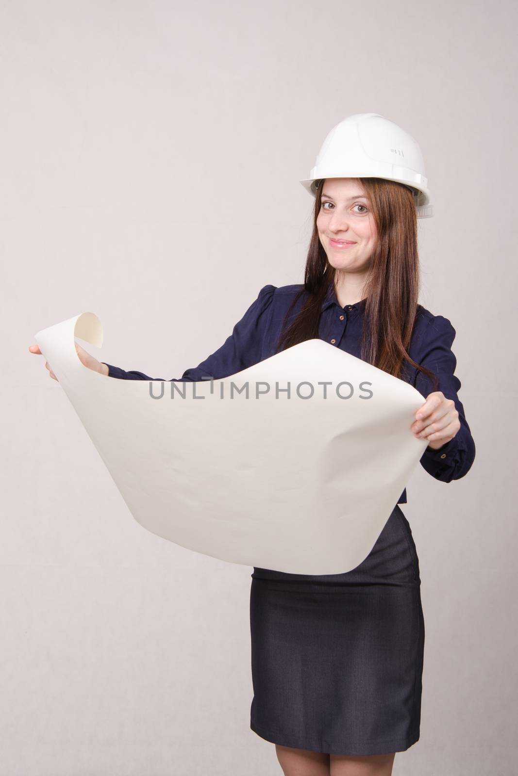 Young woman architect in hardhat standing with blueprints in hand