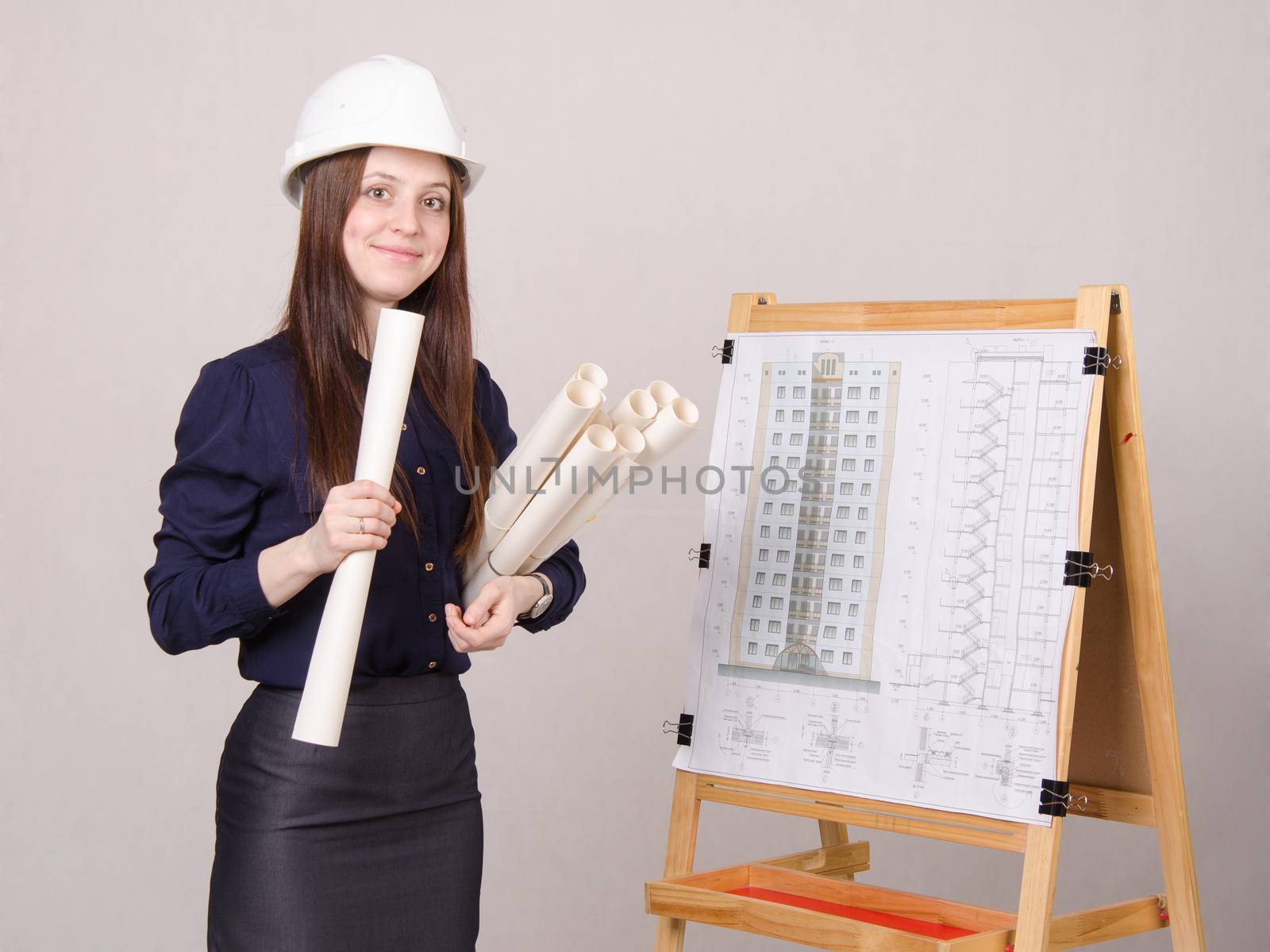 A young girl stands at the blackboard drawing multistory apartment house, in the hands of a few drawings it