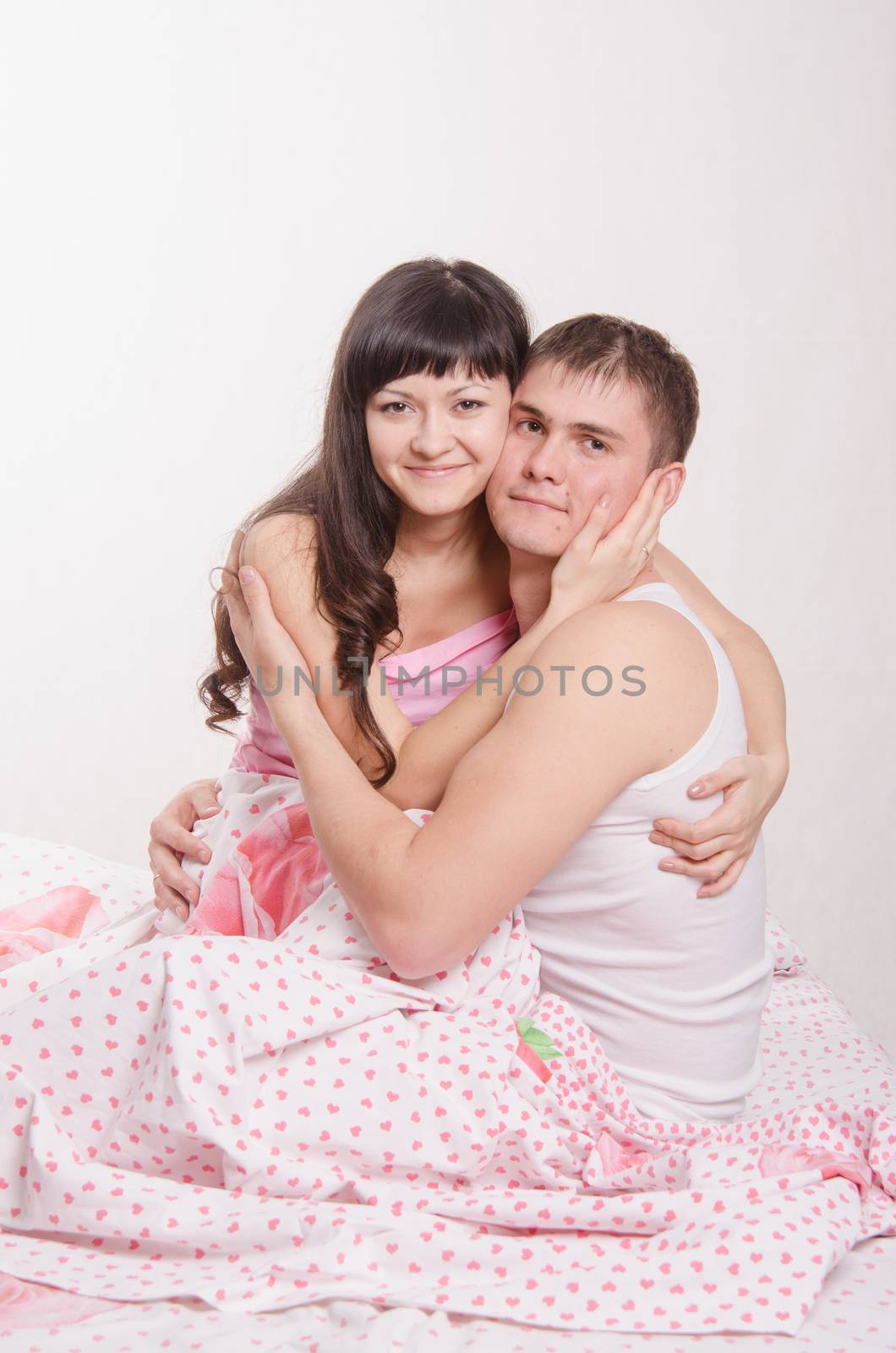 Young couple sitting in bed and hugging each other